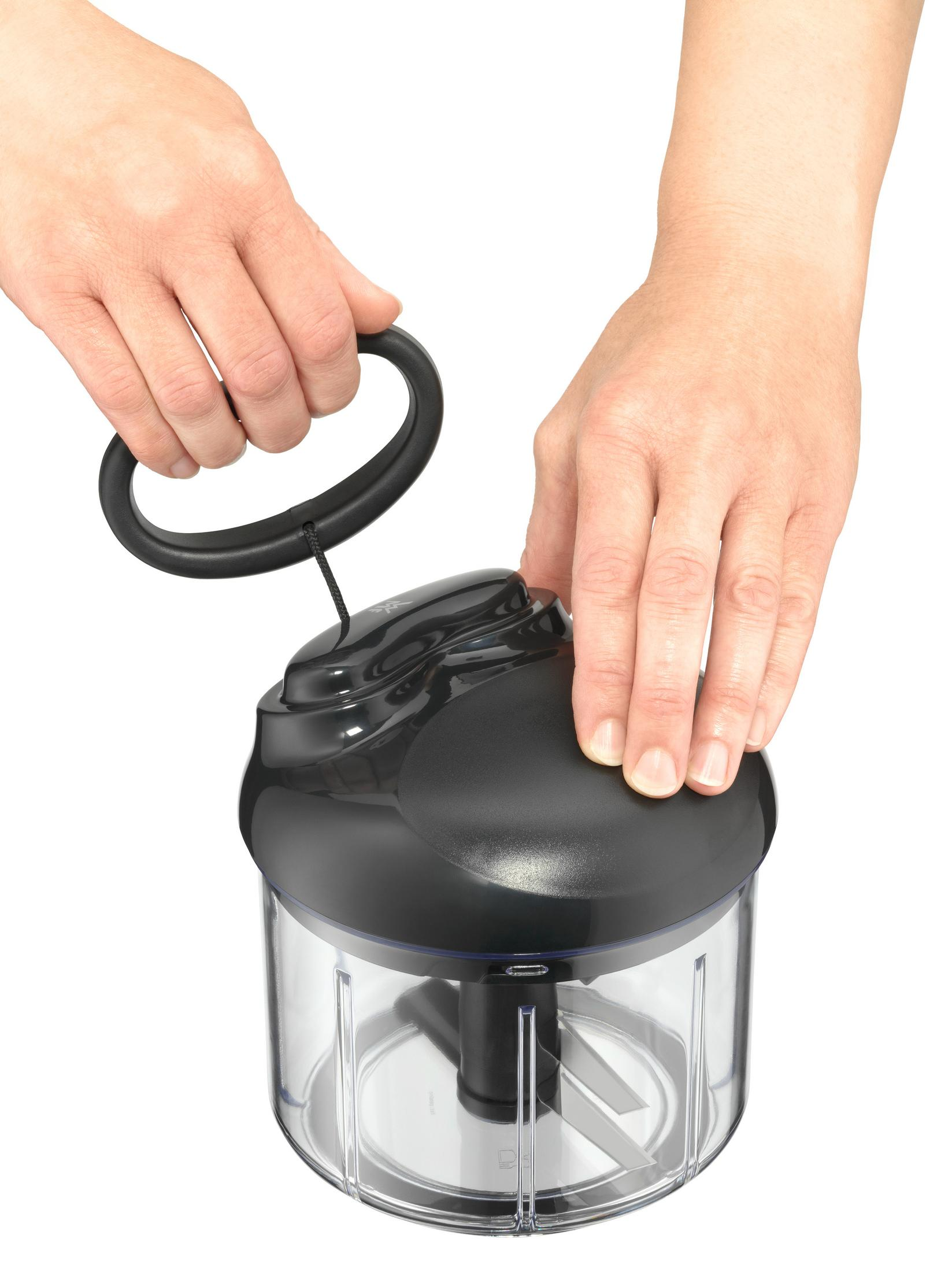 Mains utilisant un hachoir manuel noir avec poignée et lames.