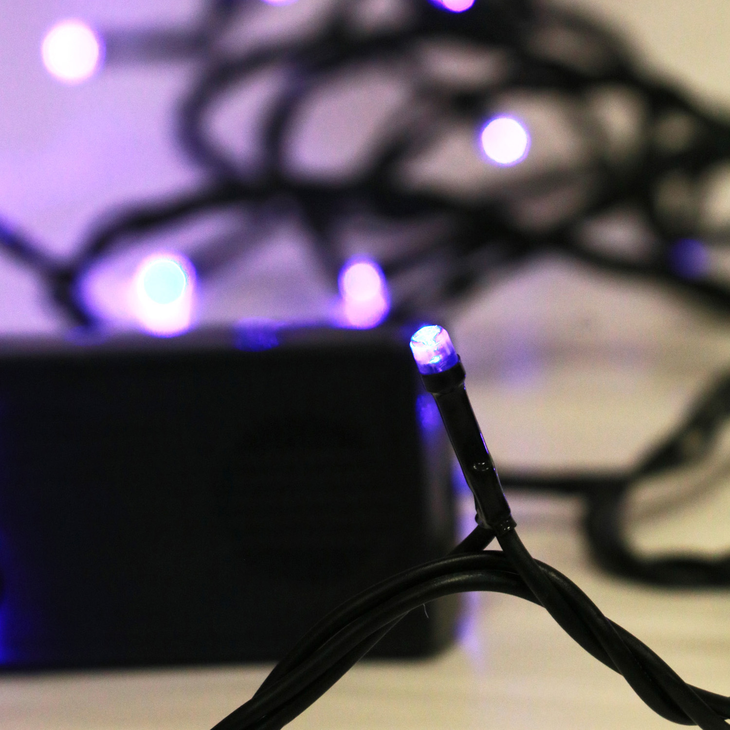 Primo piano di luci LED viola su filo nero davanti a una scatola scura.