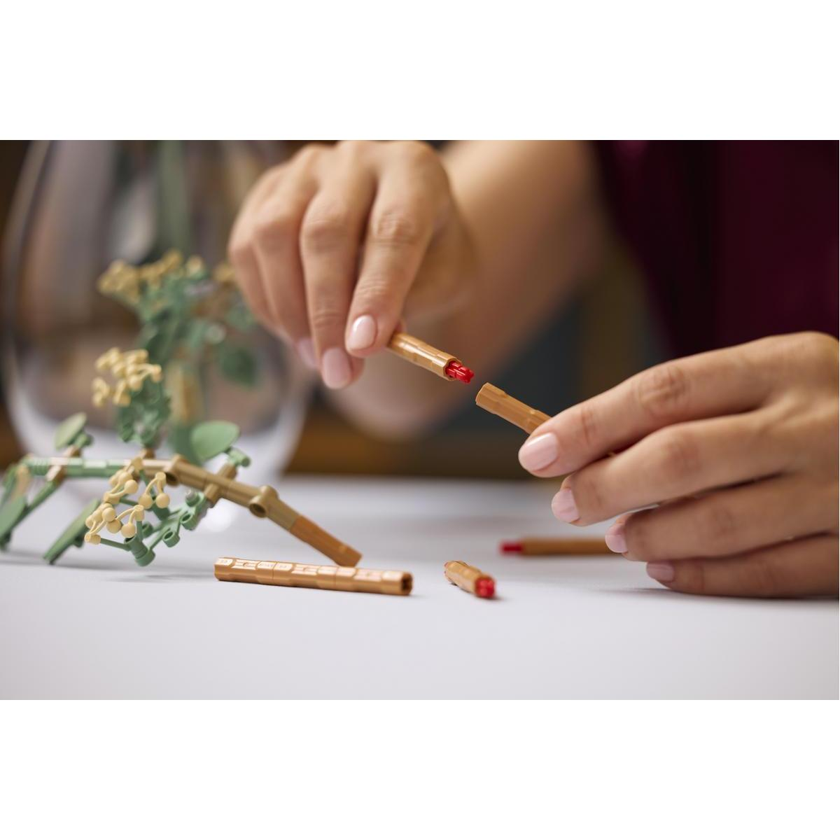 Dłonie łączą brązowe patyczki z czerwonymi końcówkami. Inne leżą obok.