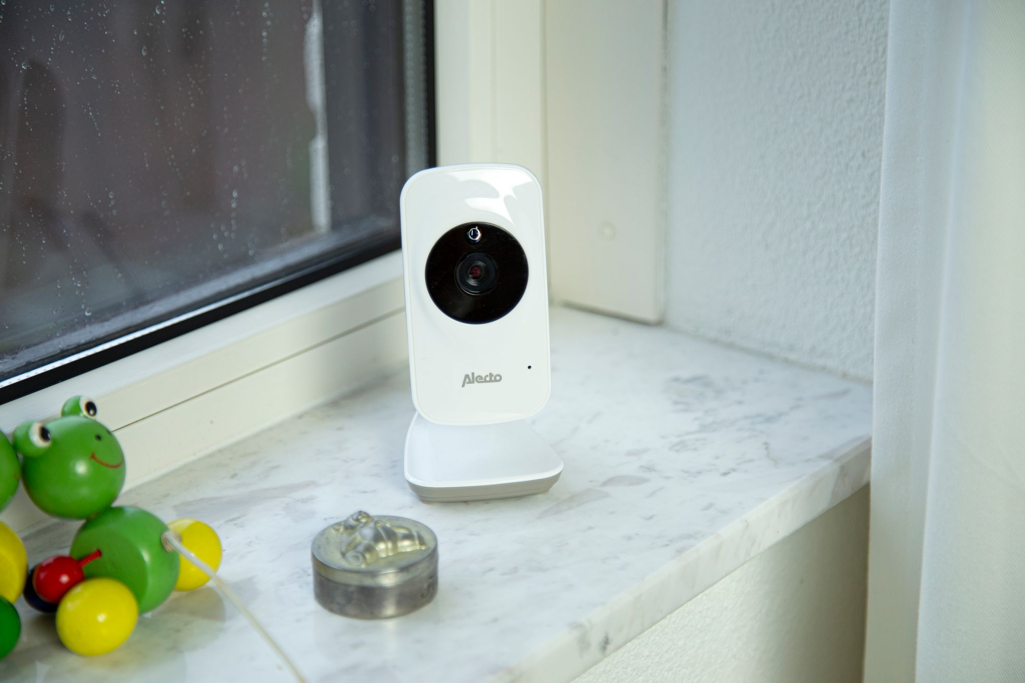 Ein weißer Baby Monitor steht auf einem Marmorsims neben einem Fenster.