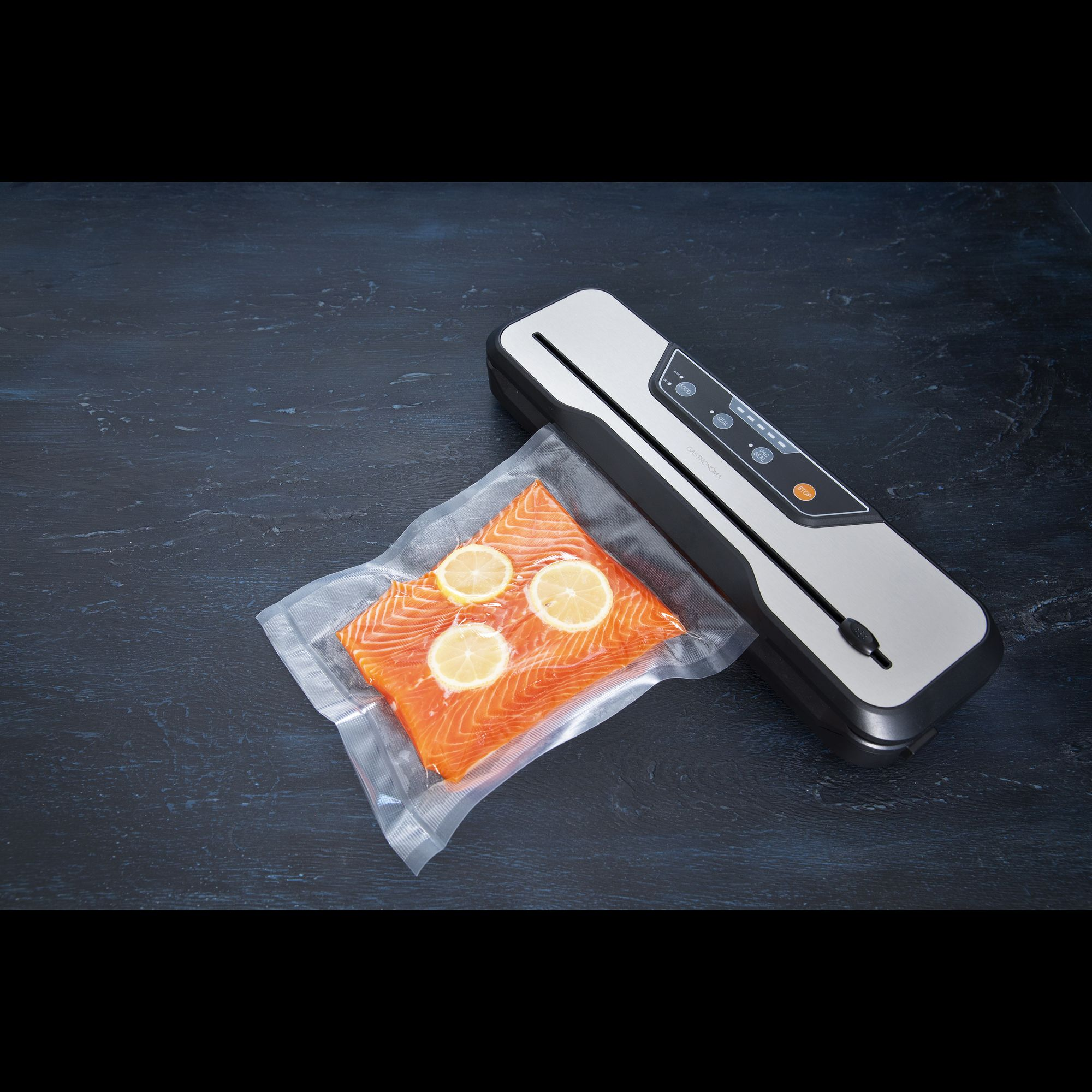 Urządzenie do pakowania próżniowego i kawałek łososia z plasterkami cytryny w worku próżniowym.