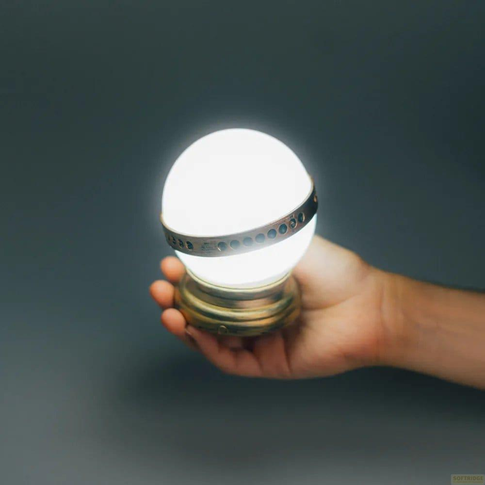 Una mano tiene un globo luminoso con base ornata su sfondo scuro.