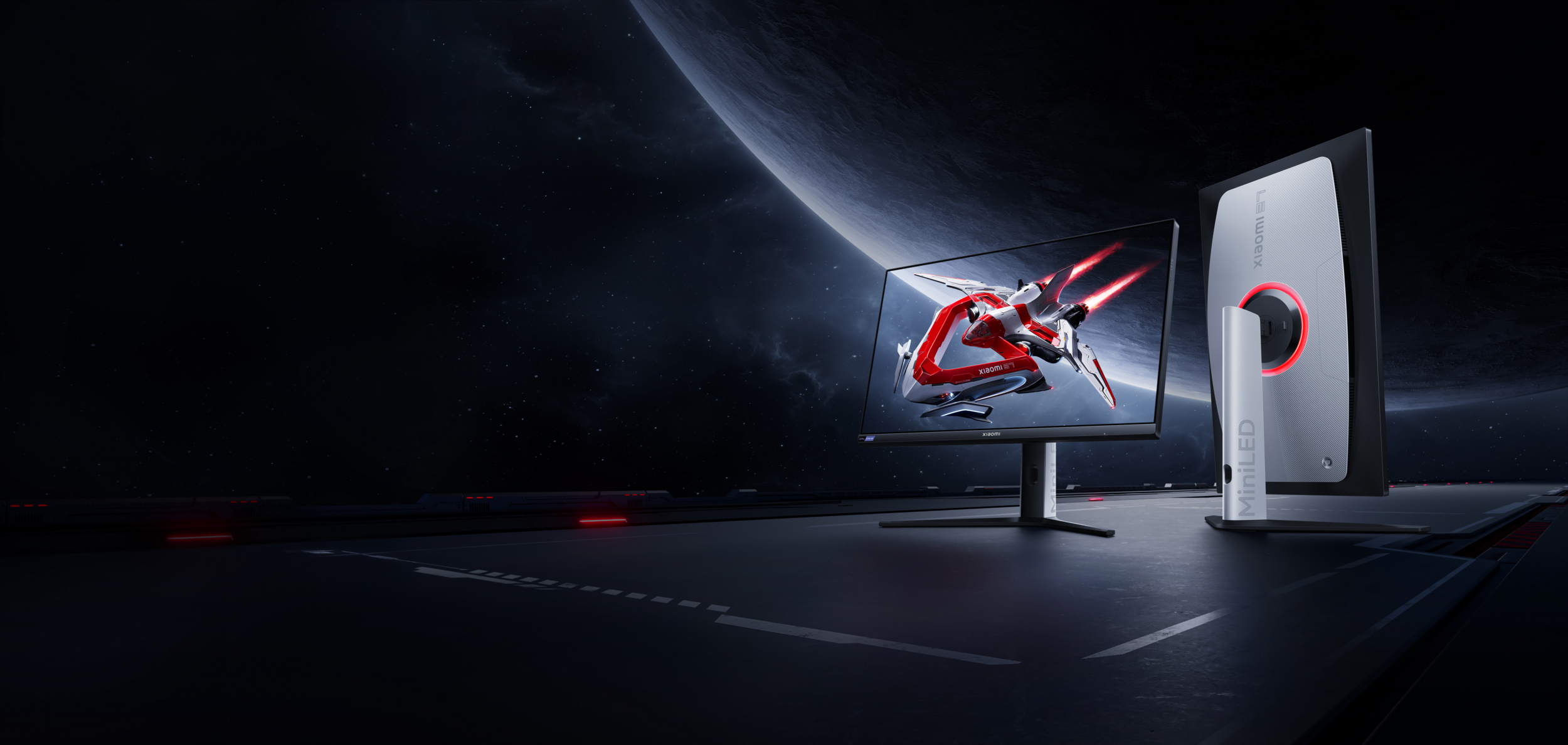 Dwa monitory Xiaomi na ciemnej, futurystycznej powierzchni z kosmicznym tłem i planetą.