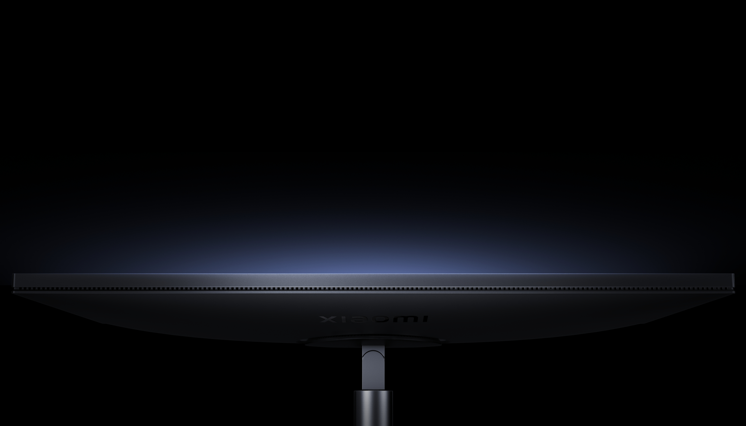 Zbliżenie ciemnego monitora z logo Xiaomi, oświetlonego od góry.