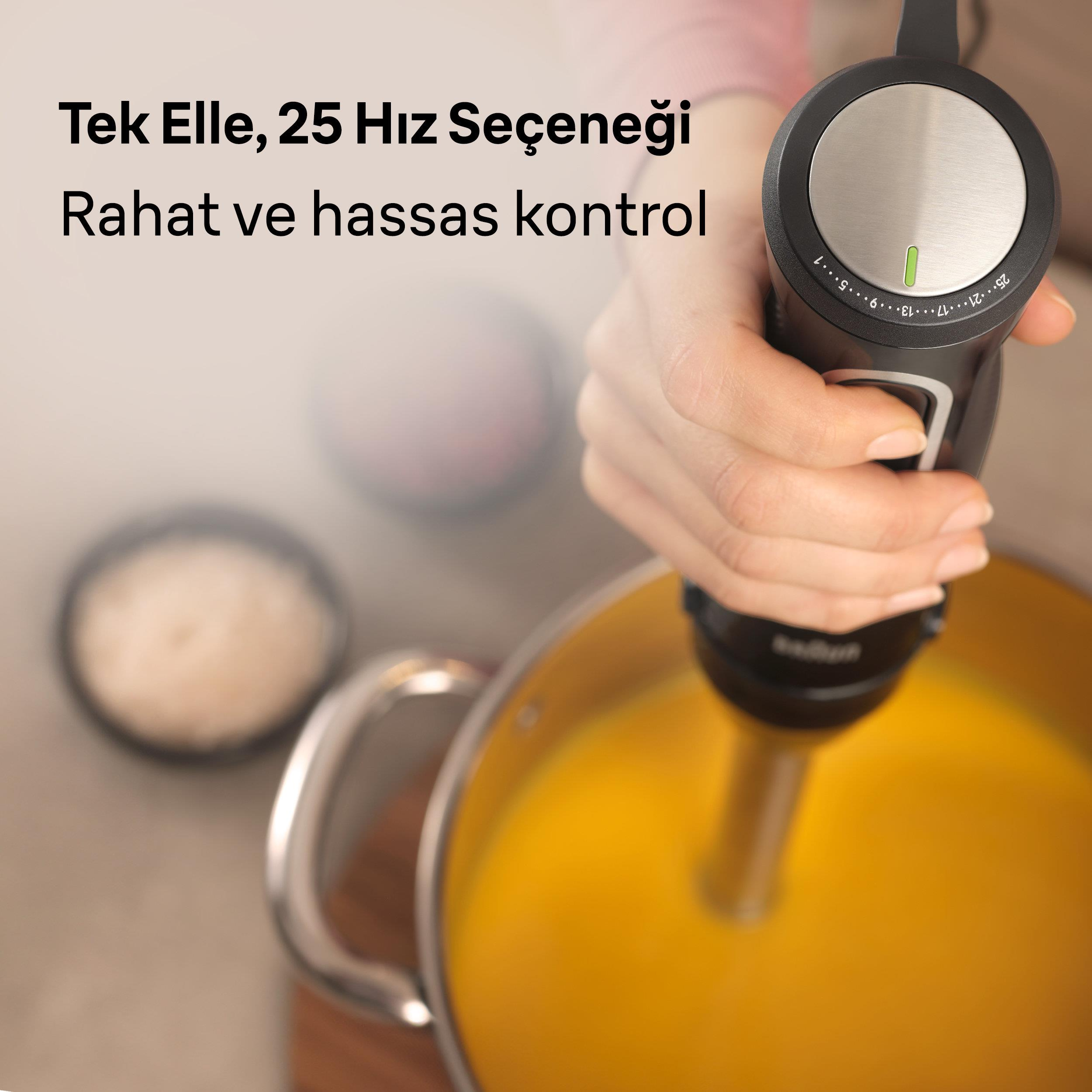 Ręka trzyma blender zanurzeniowy nad garnkiem pomarańczowego płynu.