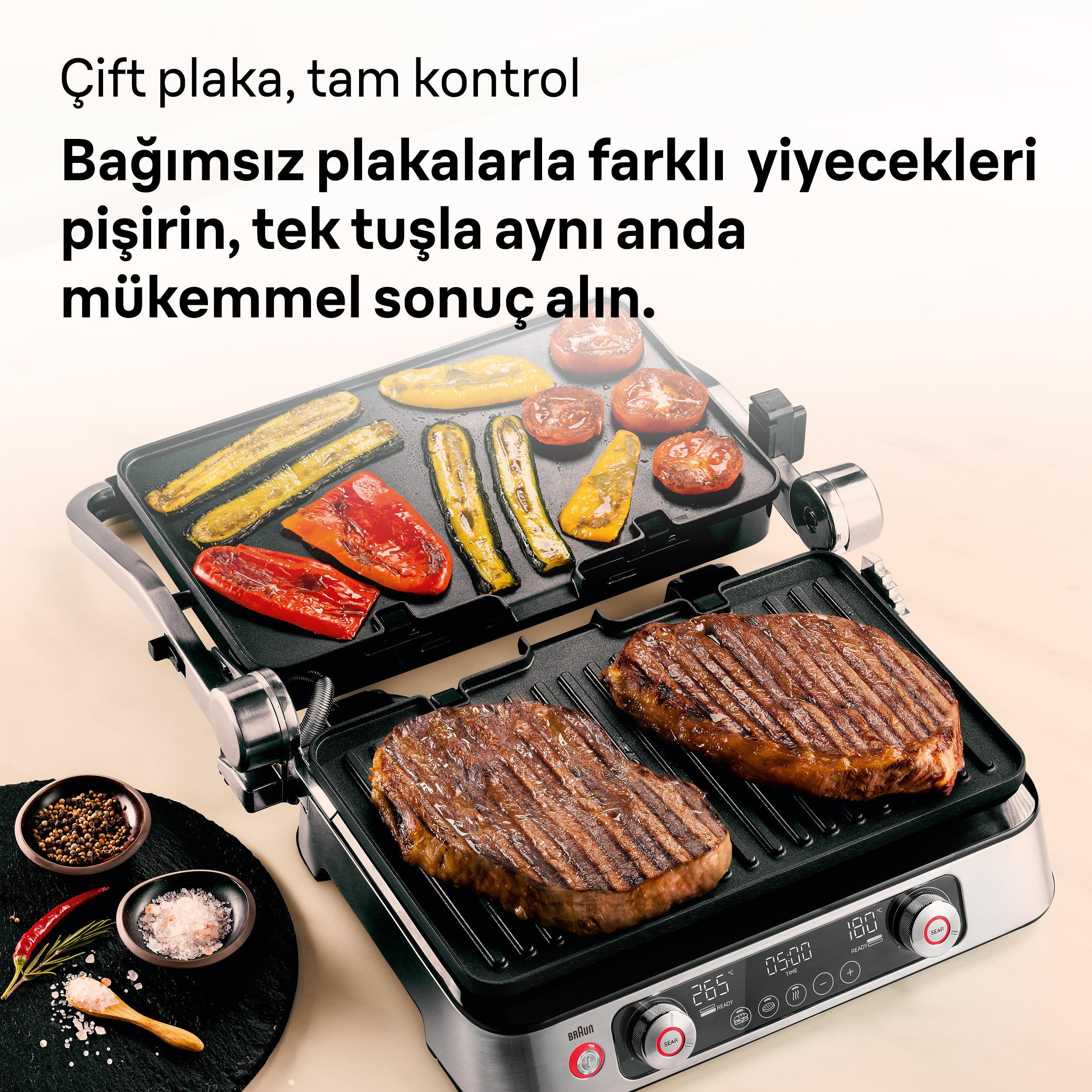 İki biftek ve ızgara sebzelerin olduğu bir grill. Yanında baharatlar.