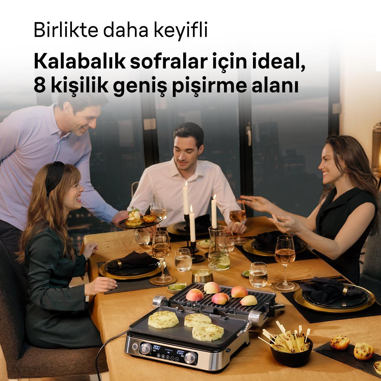 Dört kişi bir masada mangal, meyve ve mumlarla oturuyor.