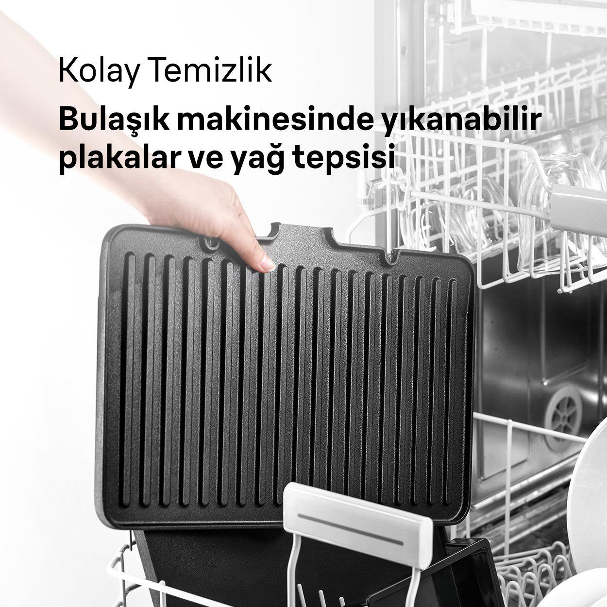 Bir el, açık bir bulaşık makinesinin önünde siyah bir ızgara tepsisi tutuyor.