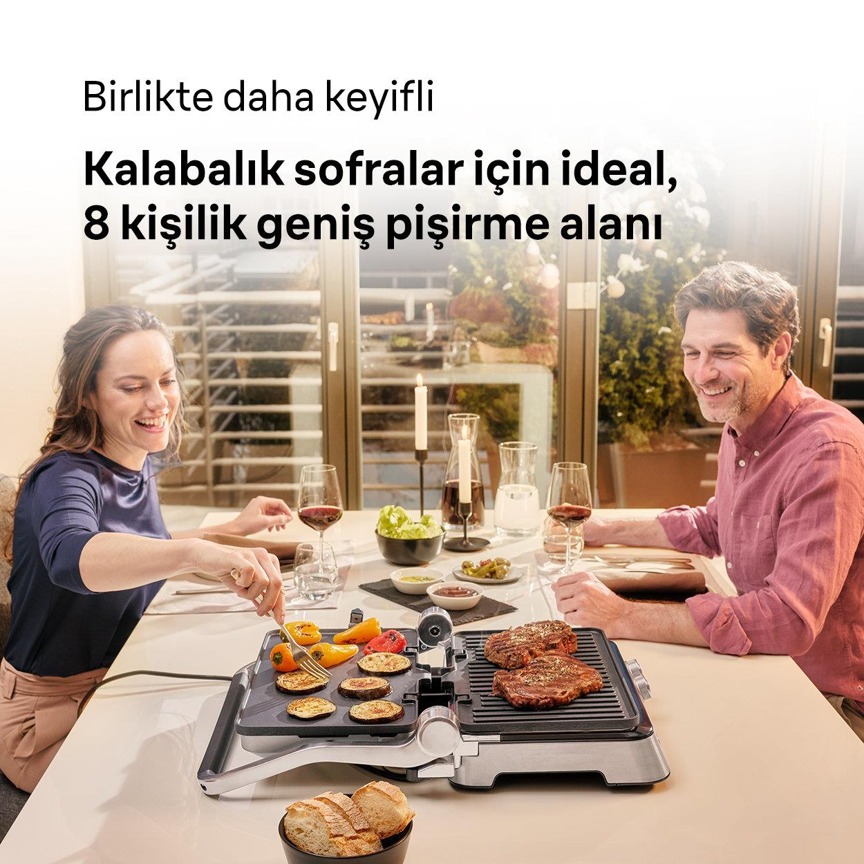 Ein Paar grillt zusammen Lebensmittel auf einem Tisch. Es gibt Steak und Gemüse.