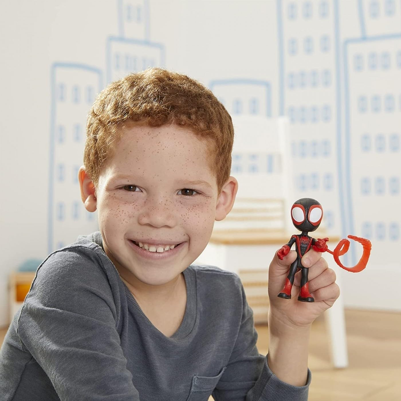 Un niño pecoso sostiene una figura de acción de Miles Morales roja y negra.