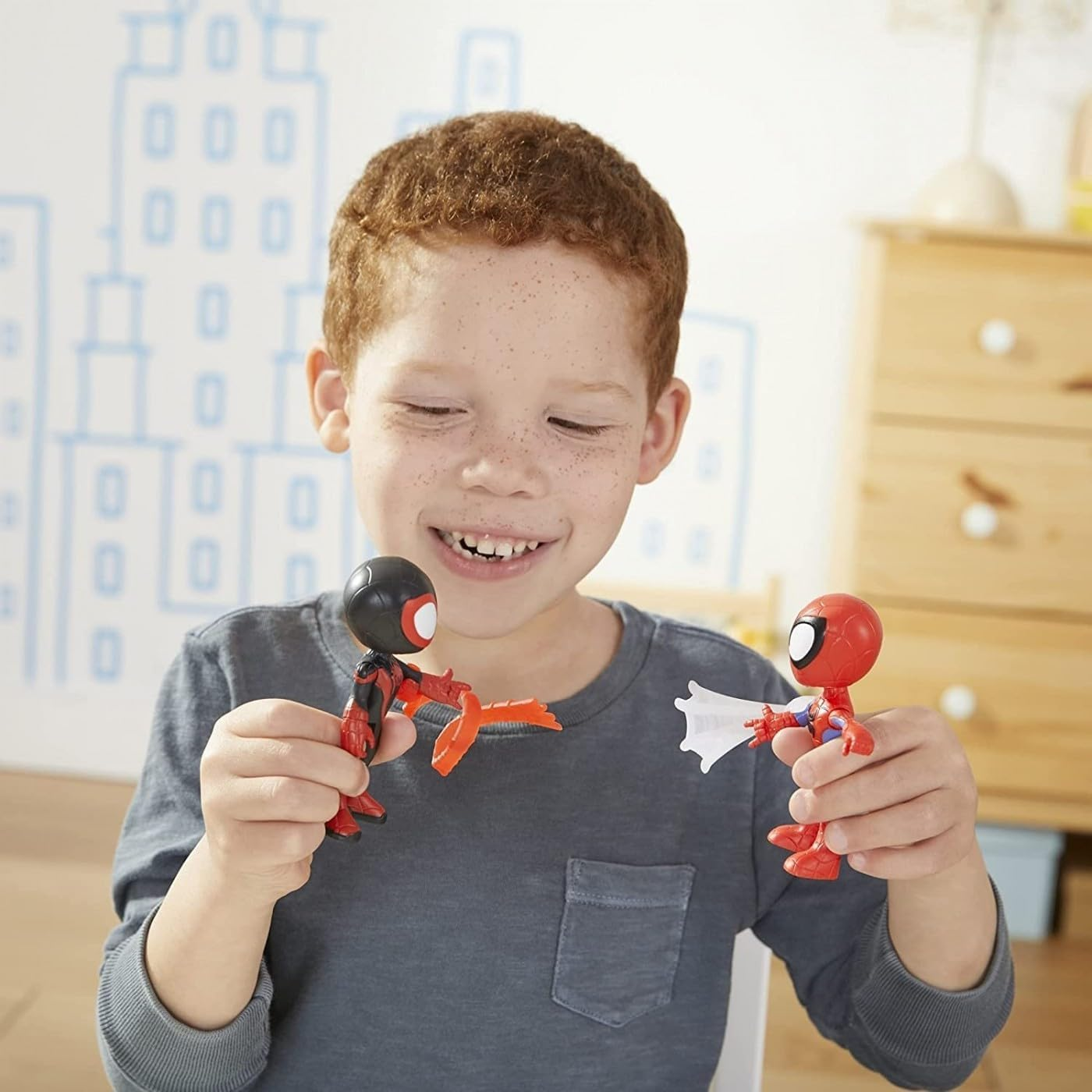 Un niño sostiene dos figuras de acción de Spiderman. Una dispara telarañas.