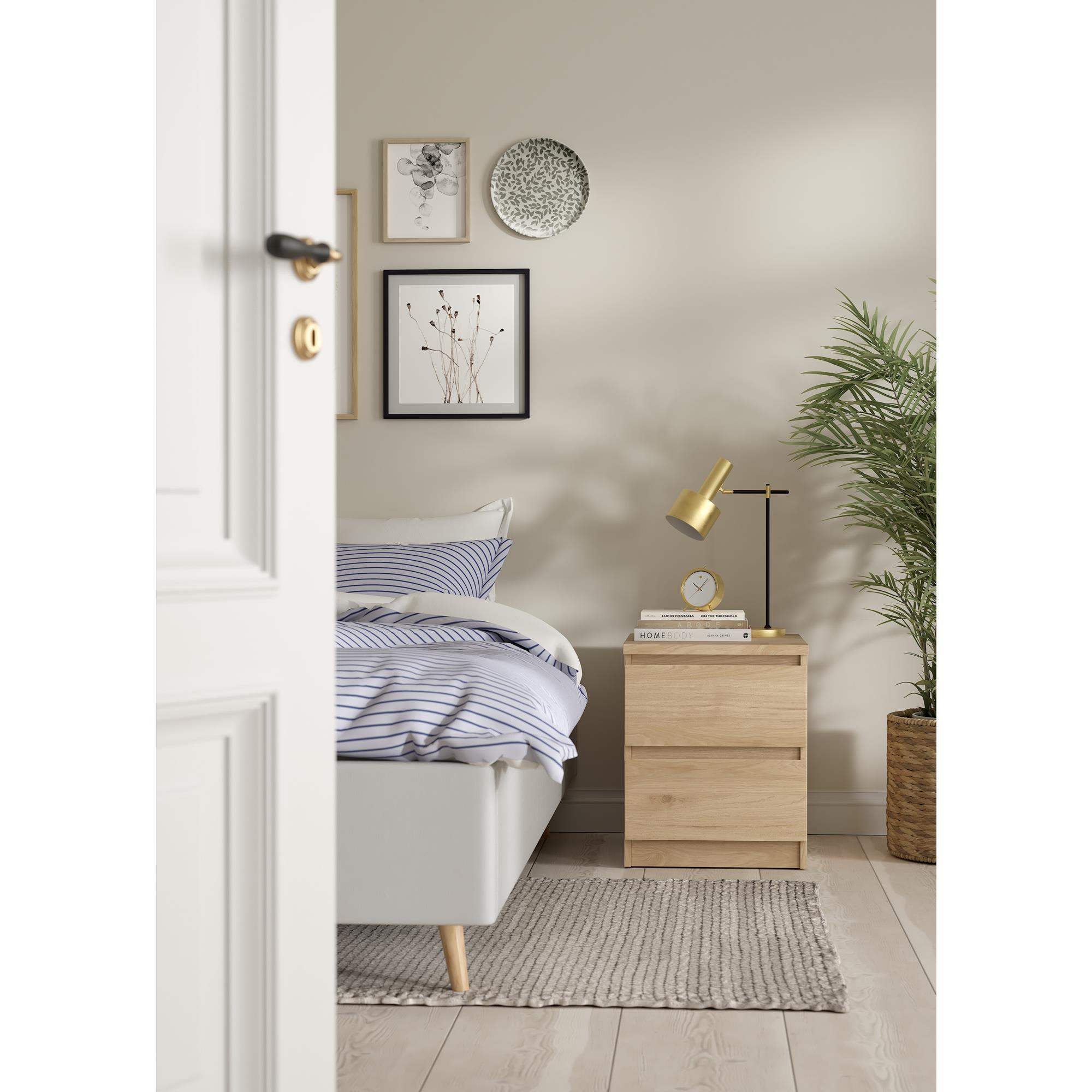 Un dormitorio con ropa de cama a rayas azules y blancas, mesita de noche y lámpara.