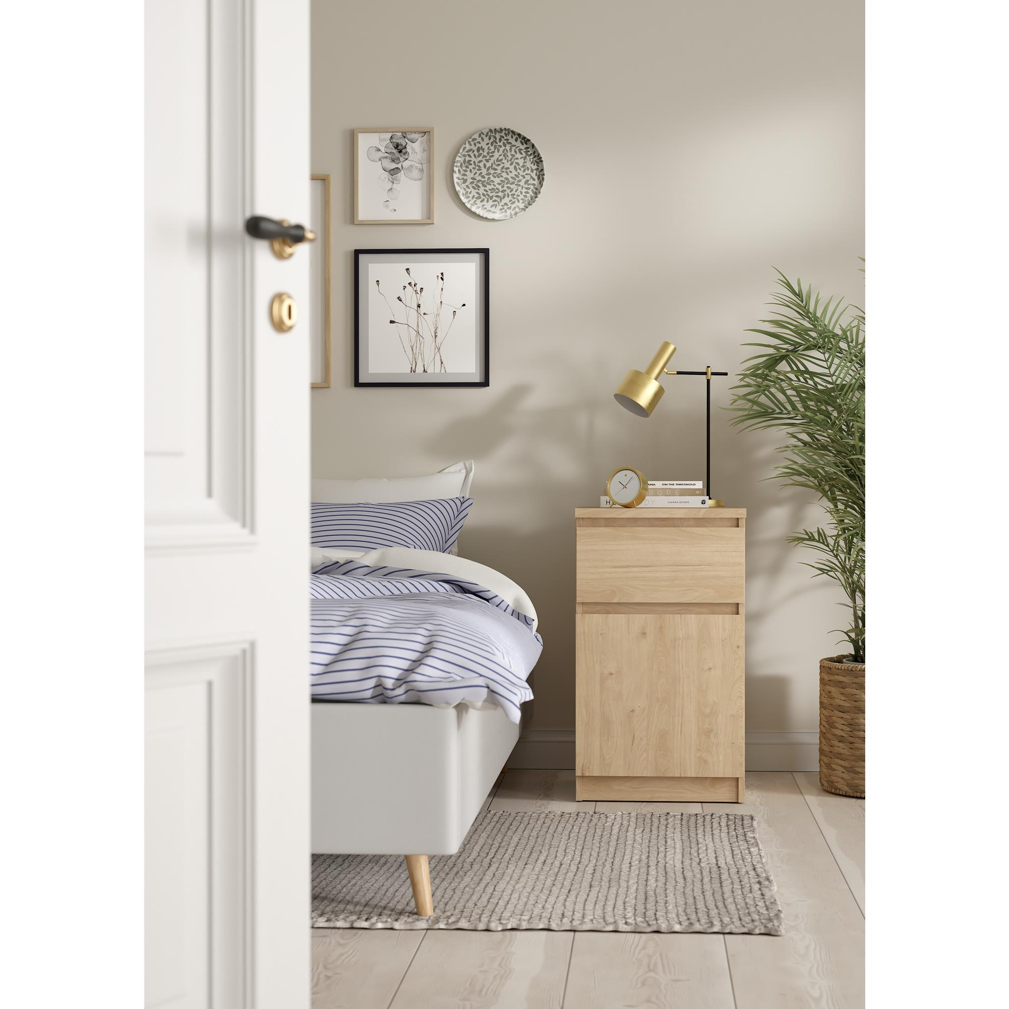 Un dormitorio con ropa de cama a rayas, mesita de noche y lámpara.