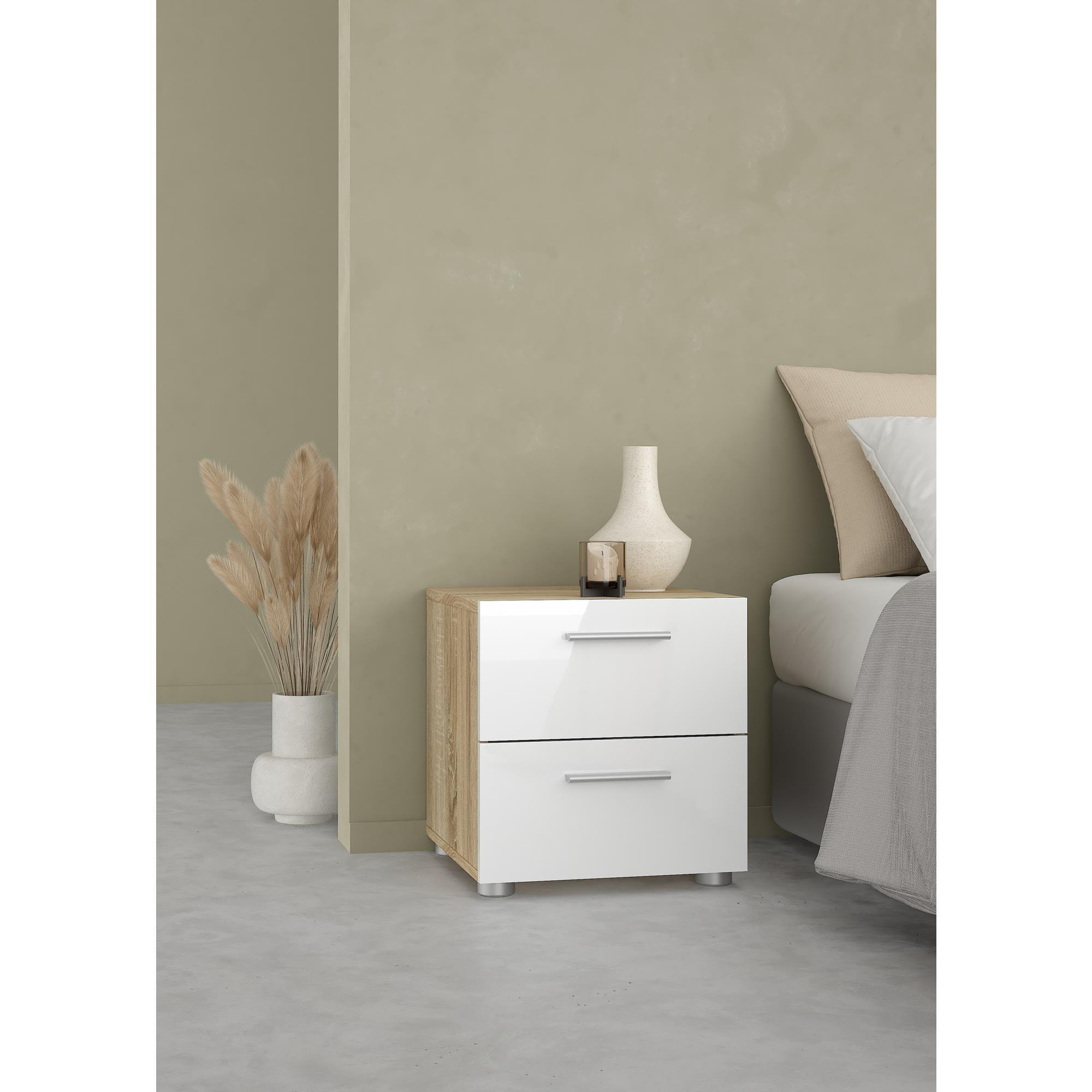 Una mesita de noche blanca de alto brillo y aspecto de madera junto a una cama.