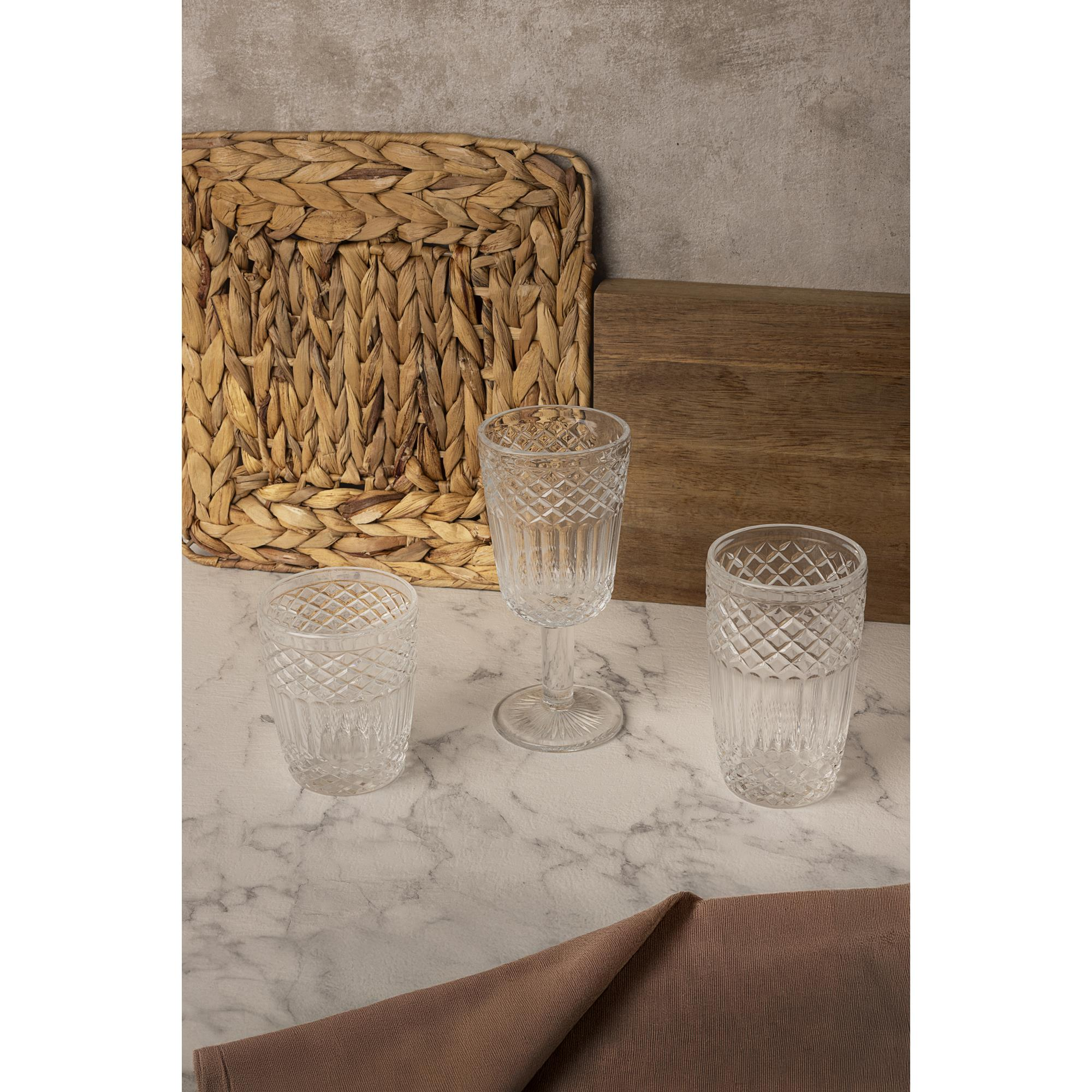 Tres vasos de cristal con patrón sobre mesa de mármol. Cesta tejida al fondo.