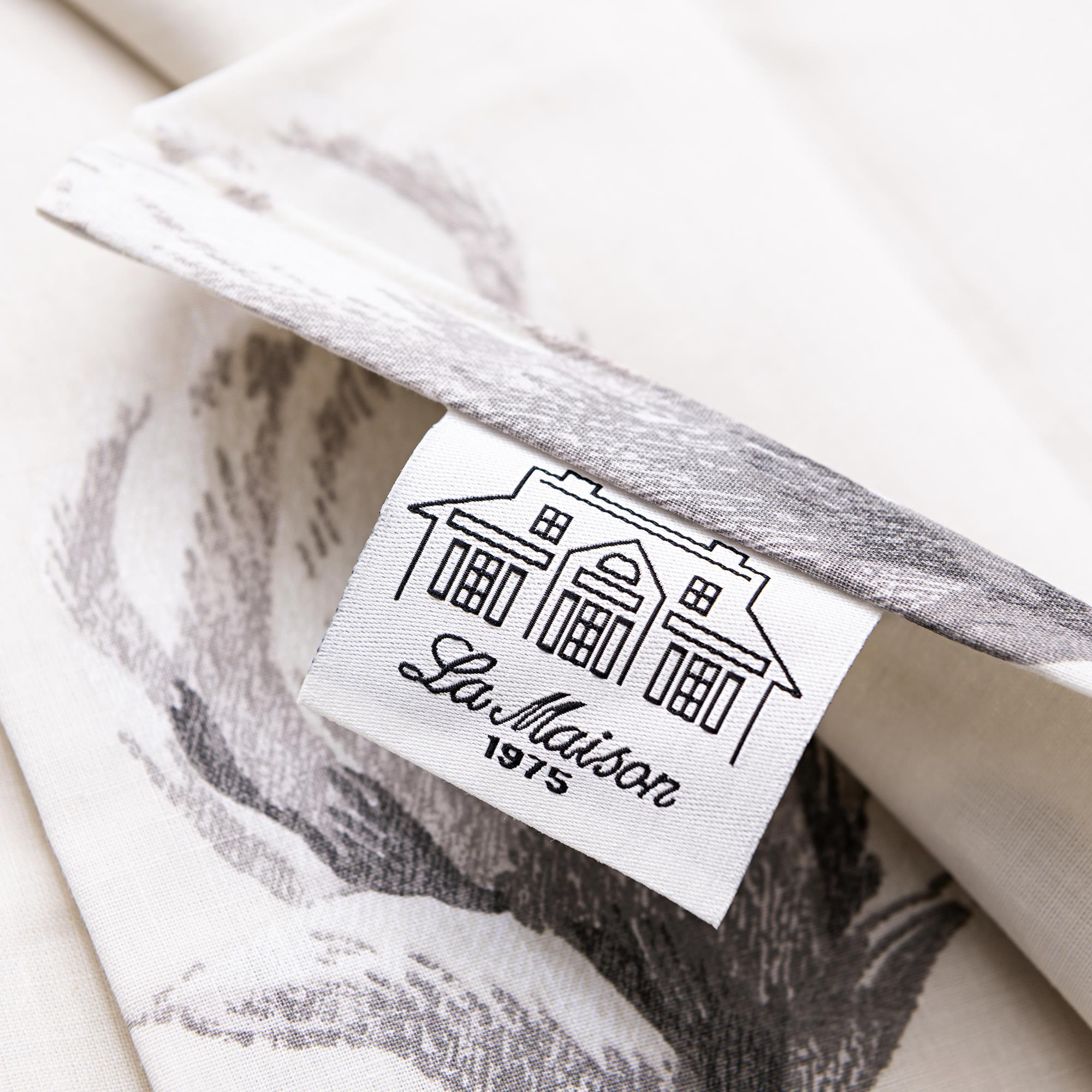 Una etiqueta blanca con texto negro y gráfico de casa sobre tela estampada.
