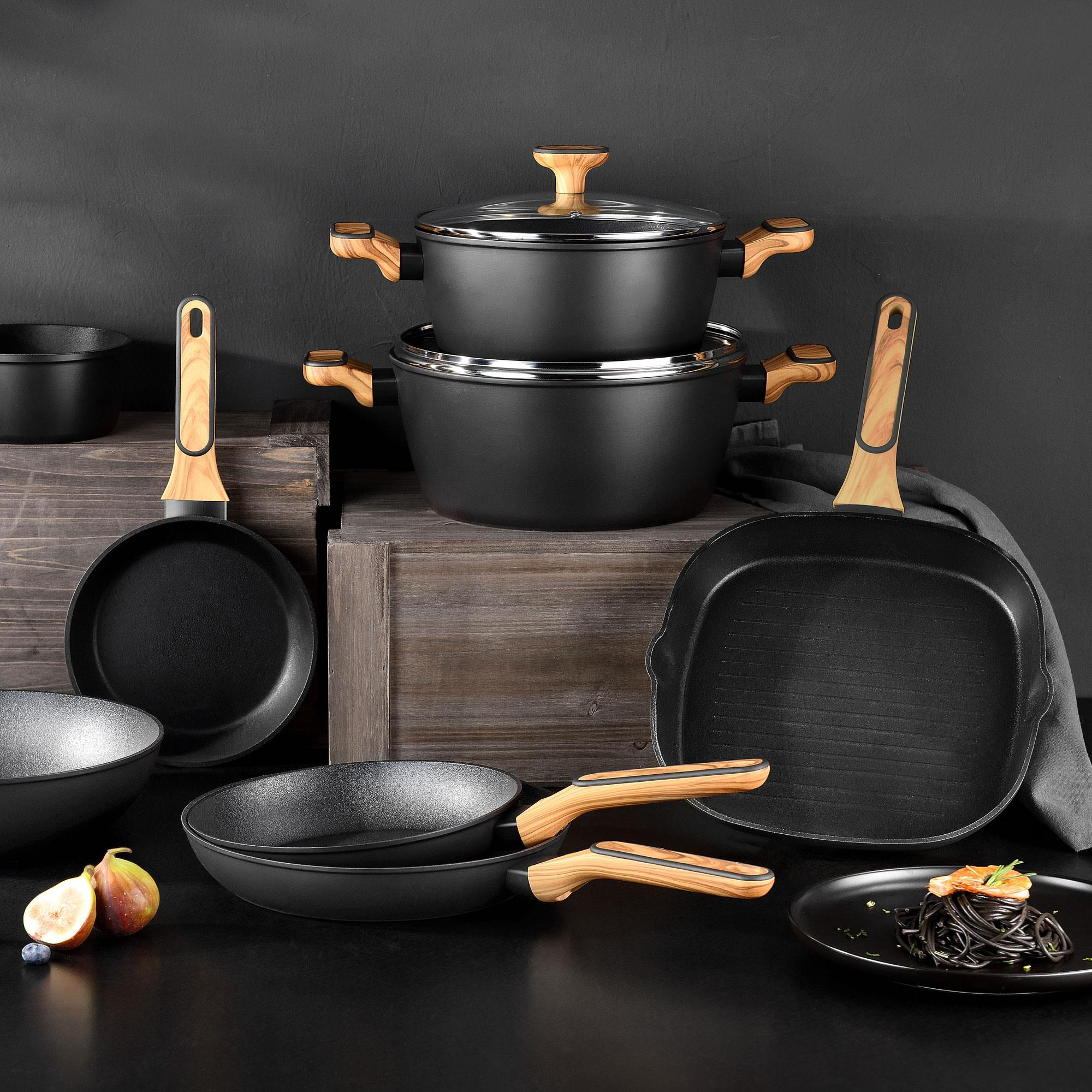 Utensilios de cocina negros con mangos de madera, junto a pasta con camarones.