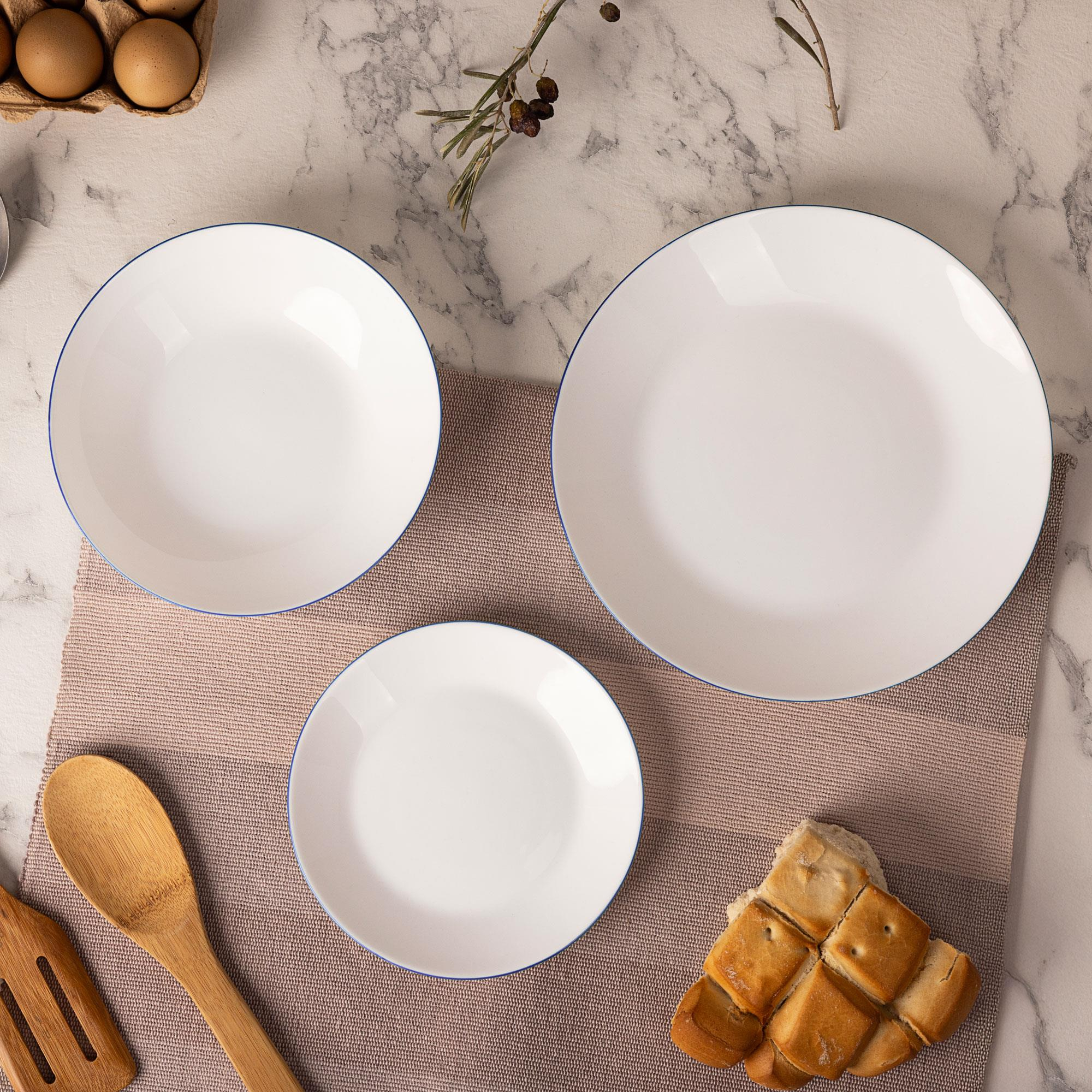 Tres platos blancos con borde azul, huevos, pan y utensilios de madera.