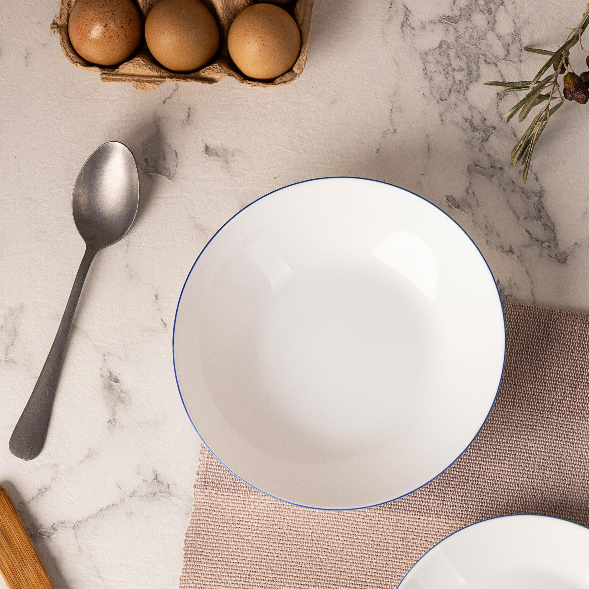Huevos en cartón, cuchara, plato y rama de olivo sobre mármol.