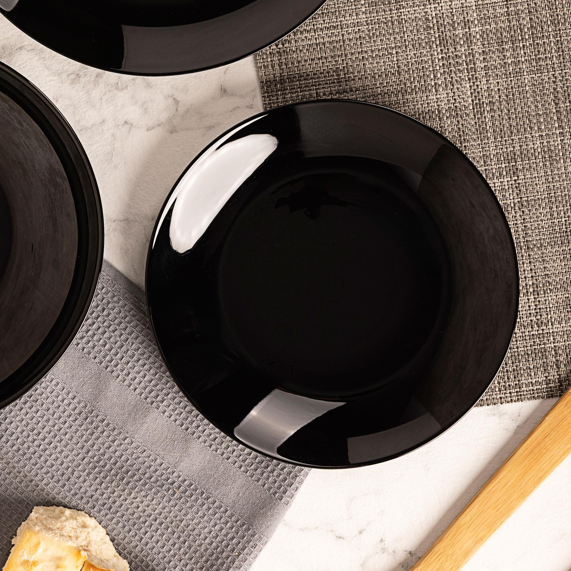 Platos negros sobre superficie de mármol con textiles.