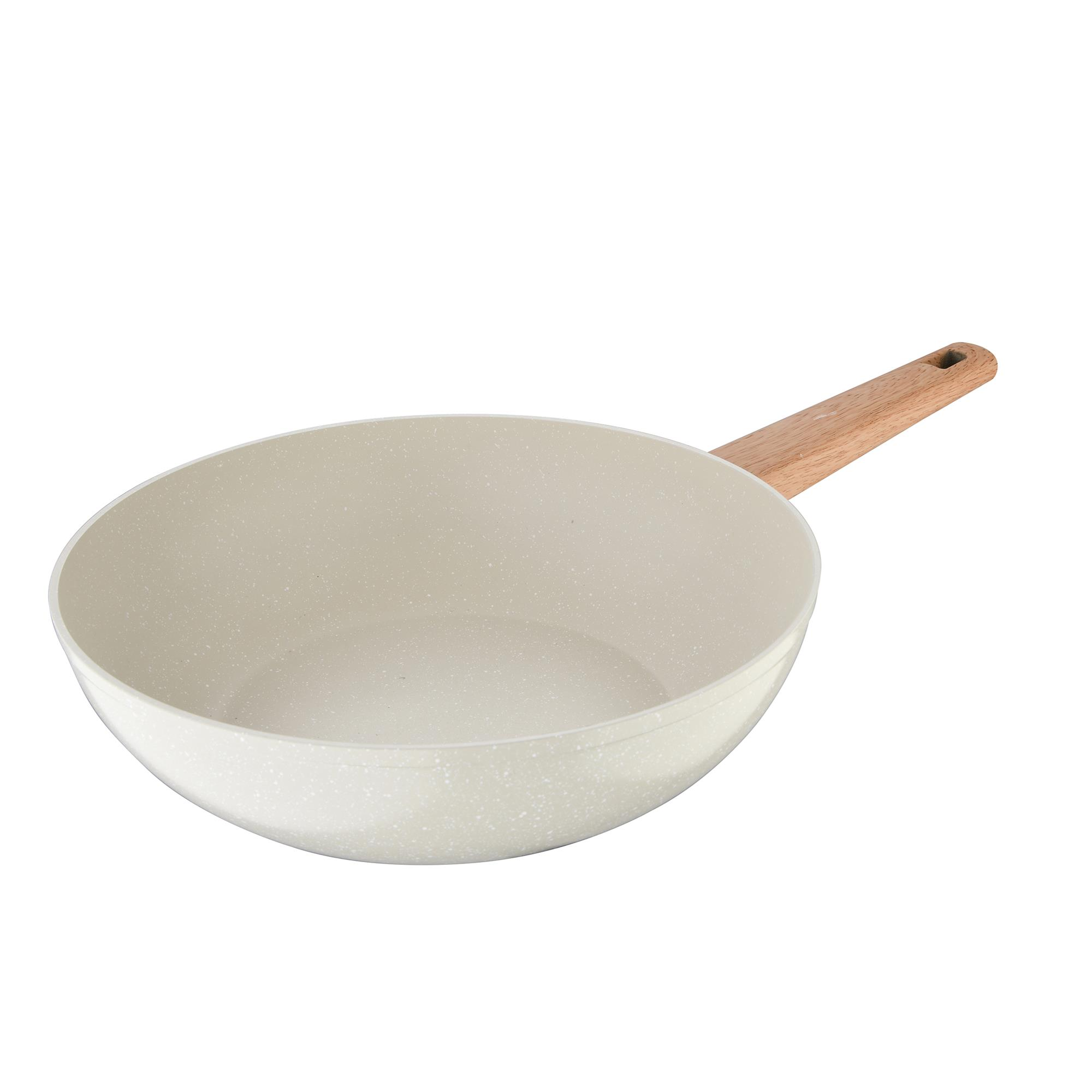 Una sartén de color claro y moteado con mango de madera.