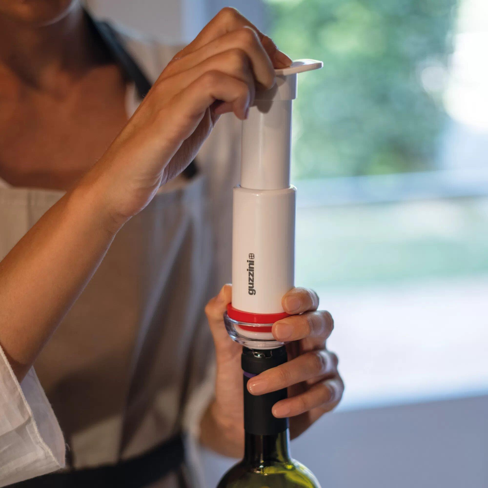 Persona usa un tapón de bomba de vino blanco en una botella verde.