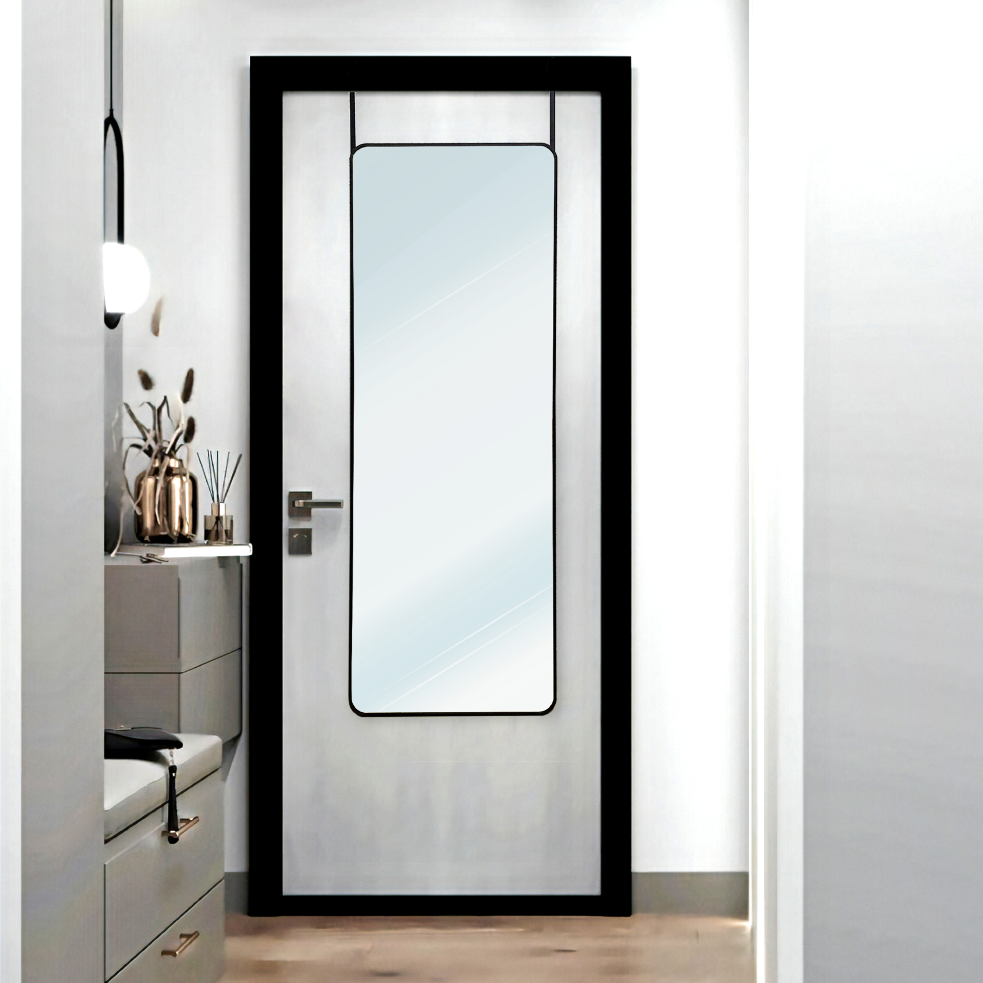 Un espejo alto cuelga de una puerta junto a una cómoda con objetos decorativos.