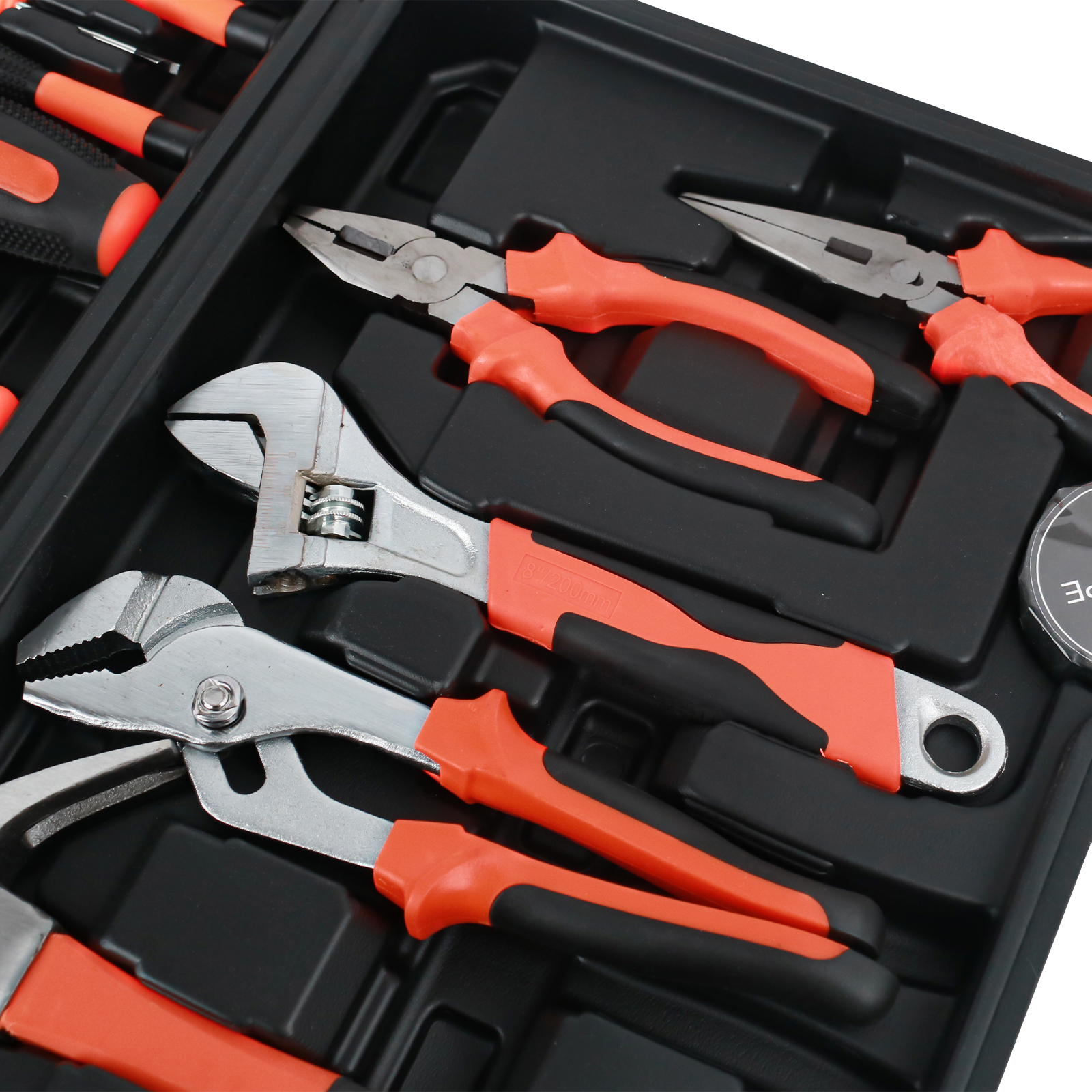 Una caja de herramientas negra con varias herramientas de mango naranja y negro, incluyendo alicates y llaves.