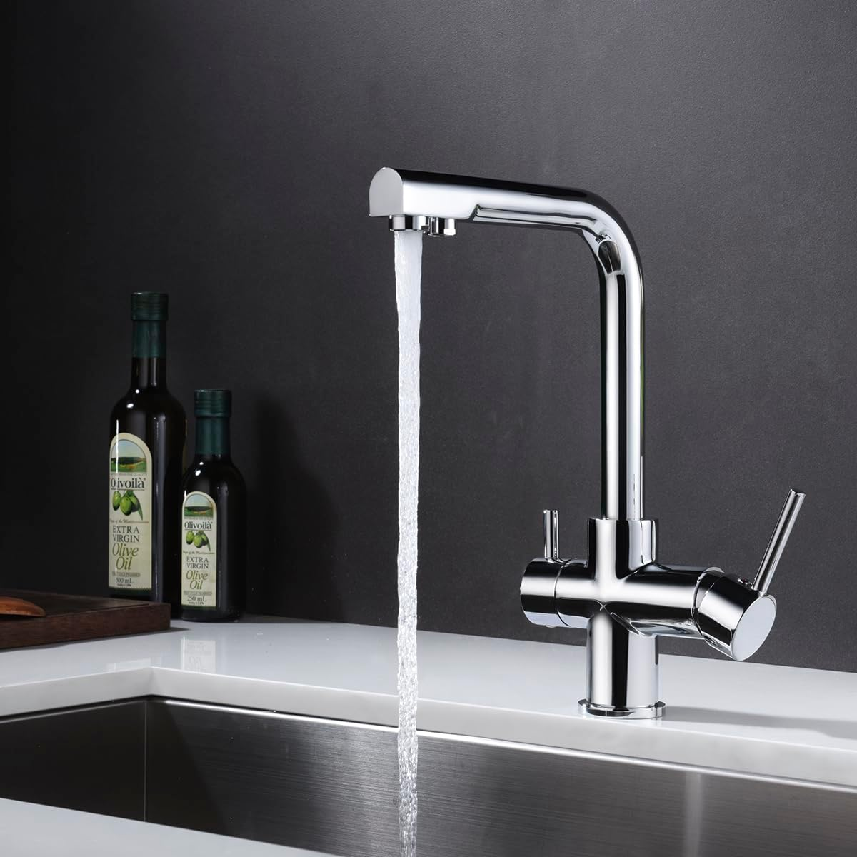 Un rubinetto cromato con acqua che scorre in un lavello, accanto a bottiglie di olio d'oliva.