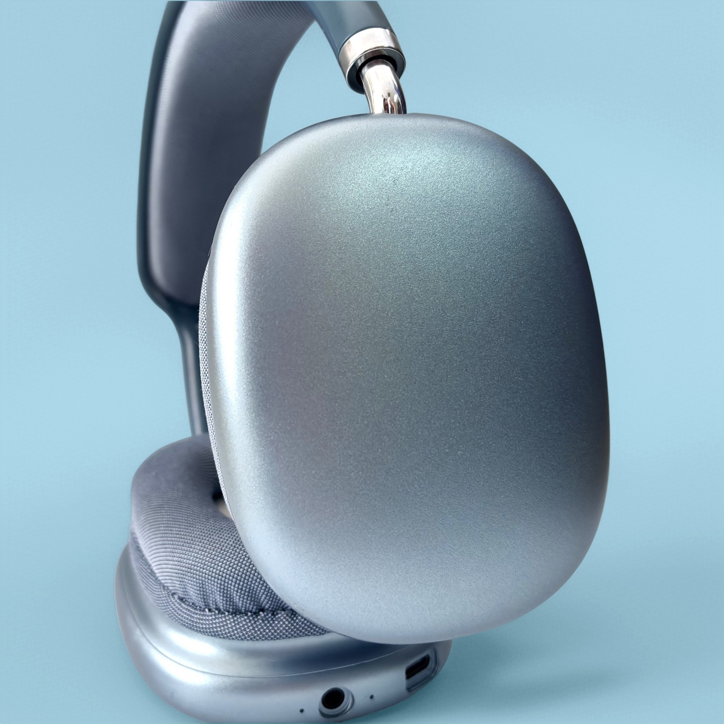 Auriculares grises con detalles plateados sobre fondo azul.