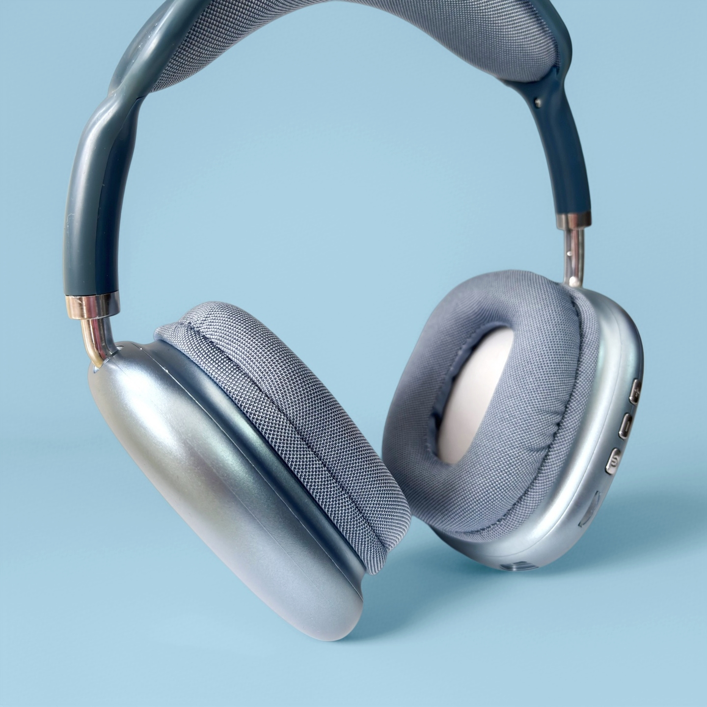 Auriculares plateados con almohadillas azules sobre fondo azul.