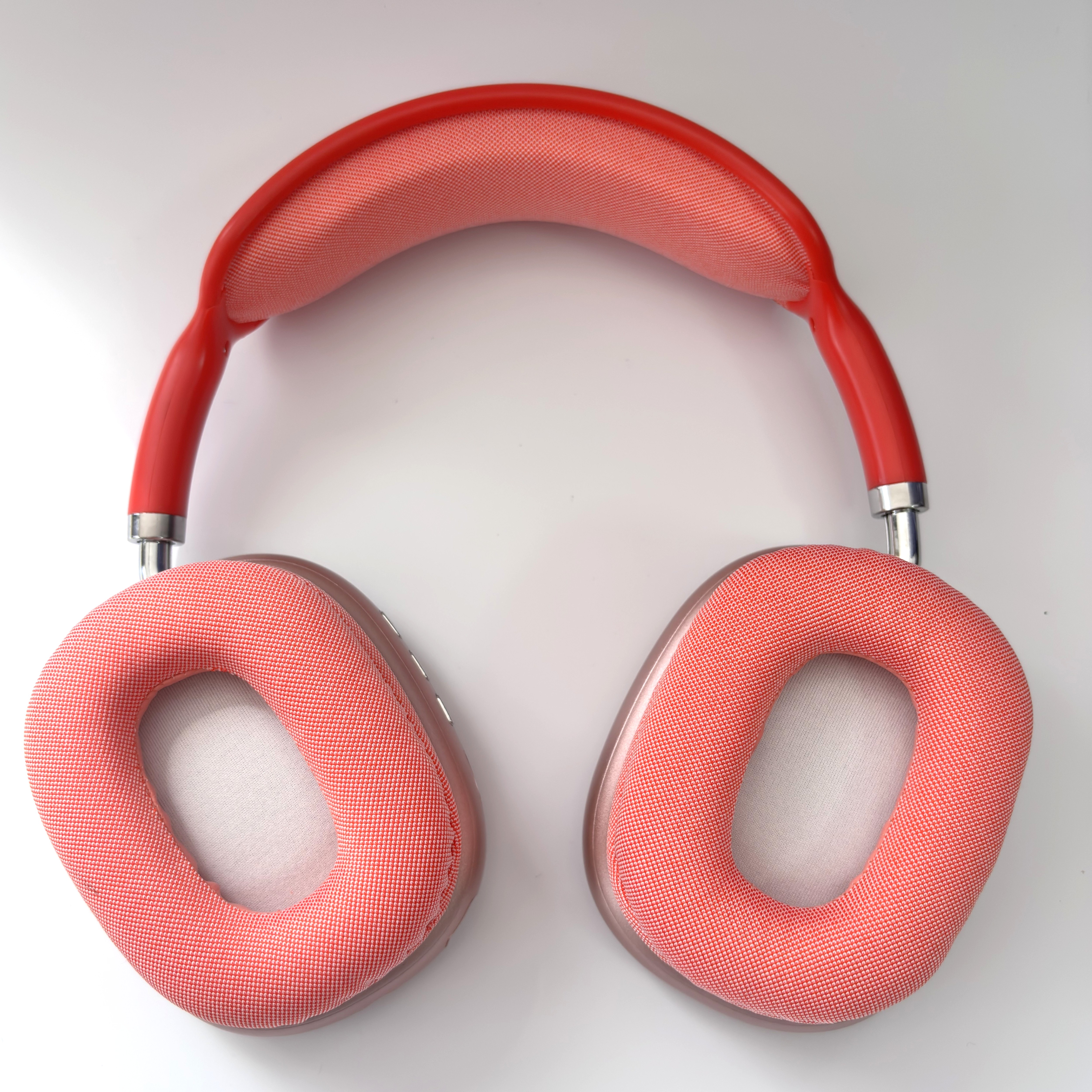 Auriculares rojos con acolchado de tela y detalles plateados sobre fondo blanco.
