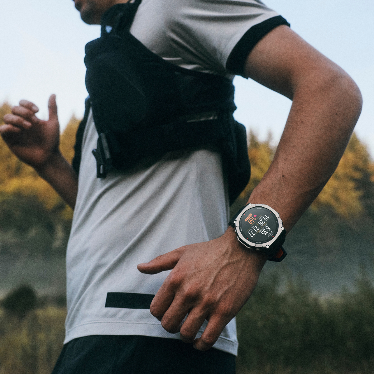 Ein Mann mit einer Weste und einem Trainingsshirt läuft im Freien. Er trägt eine Smartwatch.