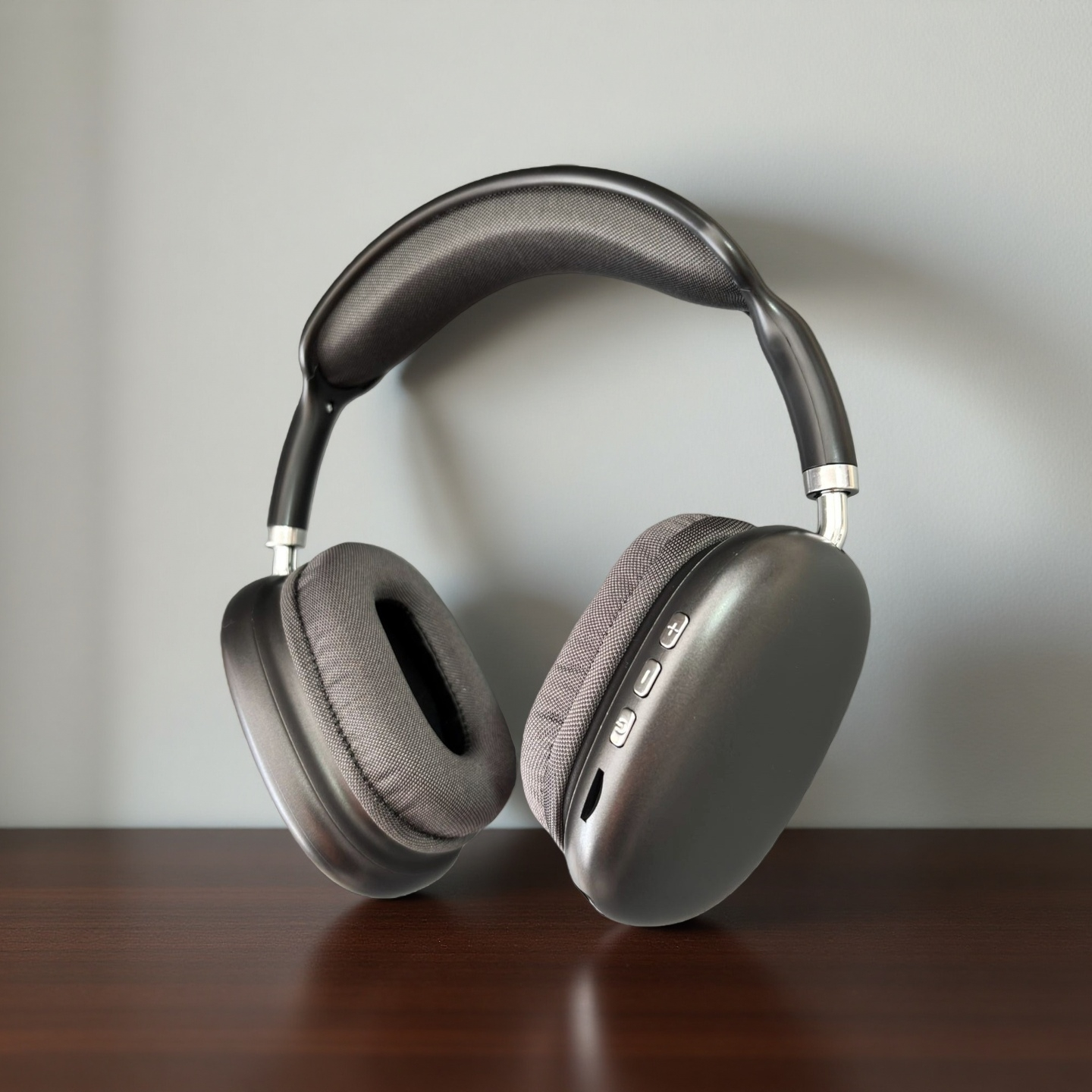 Auriculares grises oscuros supraaurales con diadema y almohadillas acolchadas sobre mesa.