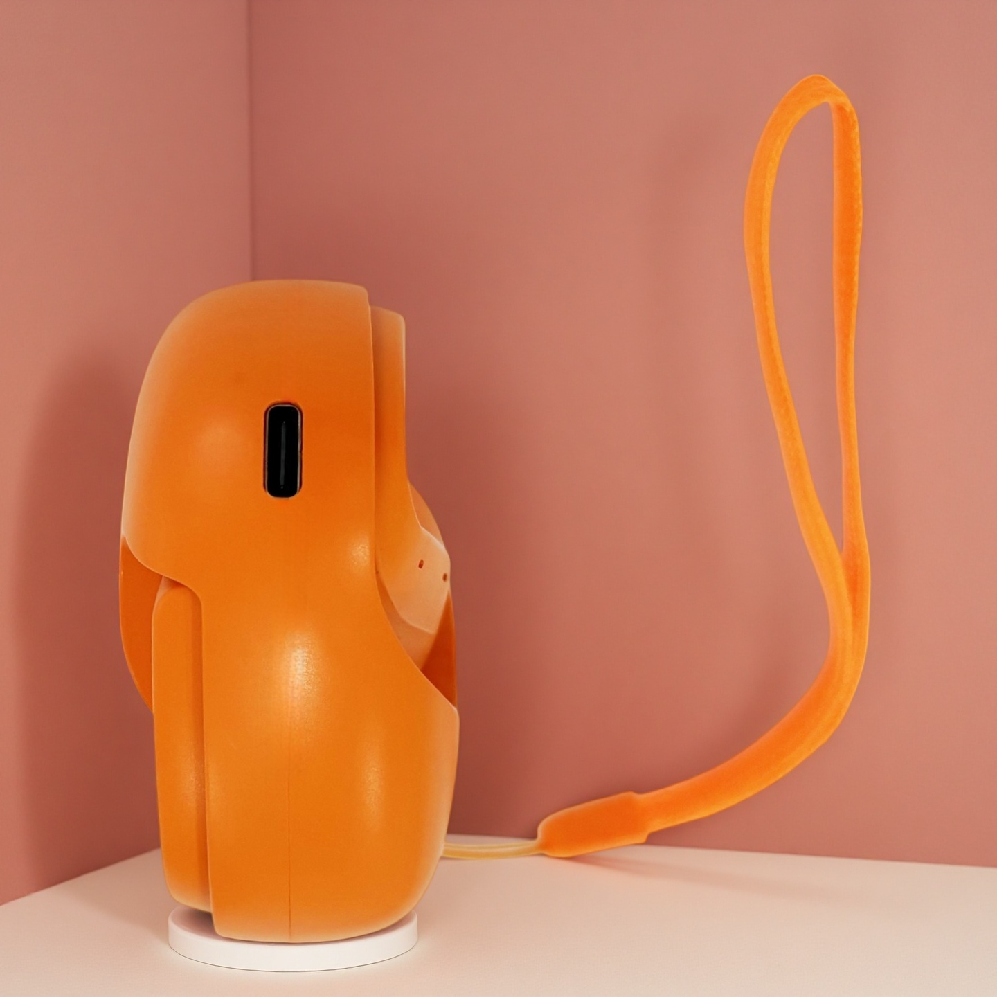 Dispositivo naranja con cordón sobre fondo rosa.