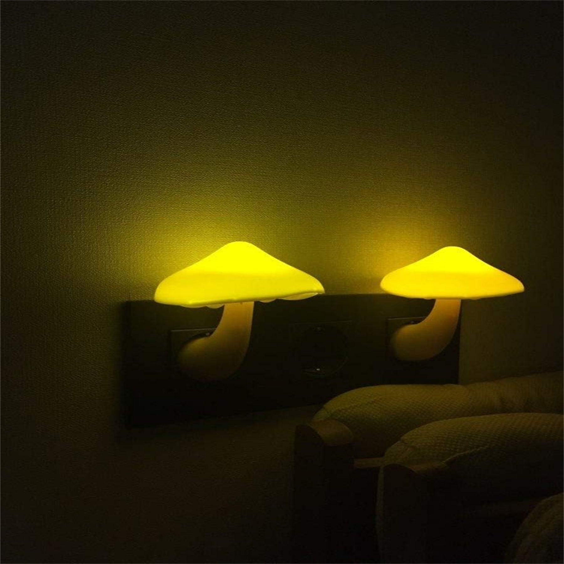 Zwei leuchtende Pilzlampen in Gelb, an einer Wandsteckdose montiert.