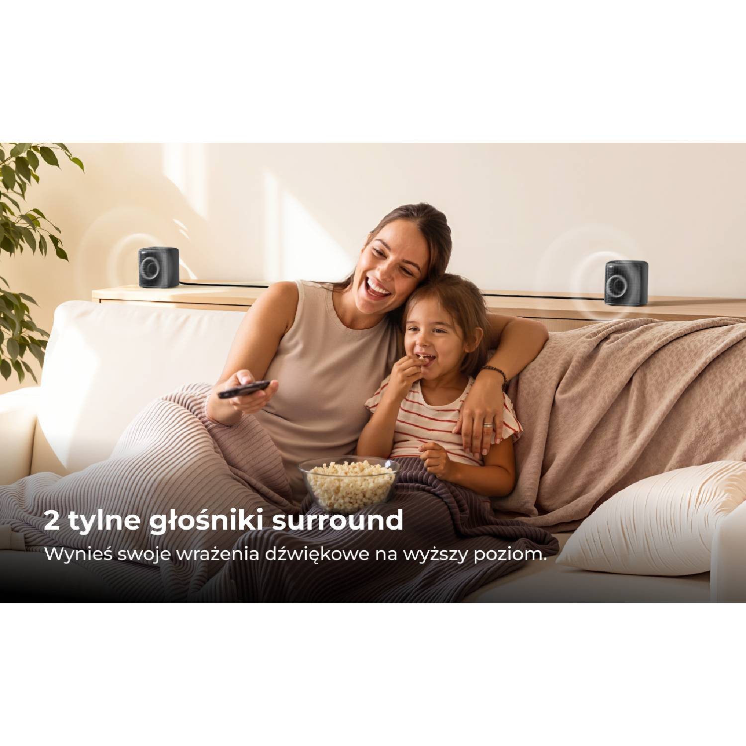 Kobieta i dziecko na kanapie z popcornem i głośnikami.