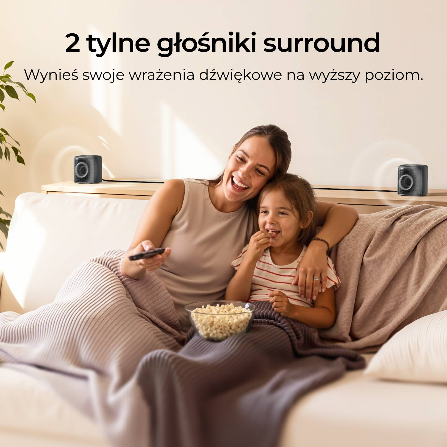 Kobieta i dziecko na kanapie z popcornem oglądają TV, dwa głośniki z tyłu.