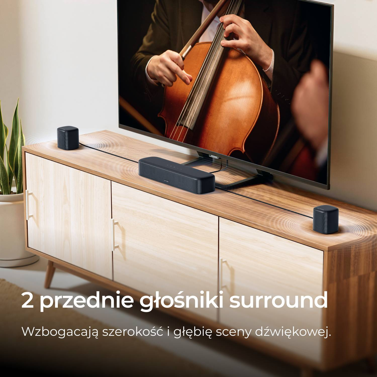 Czarny soundbar z dwoma głośnikami na drewnianej szafce przed telewizorem.