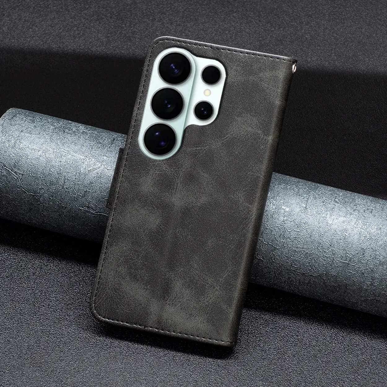 Un étui à rabat pour téléphone en cuir sombre avec un réseau d'appareils photo repose sur une surface texturée.