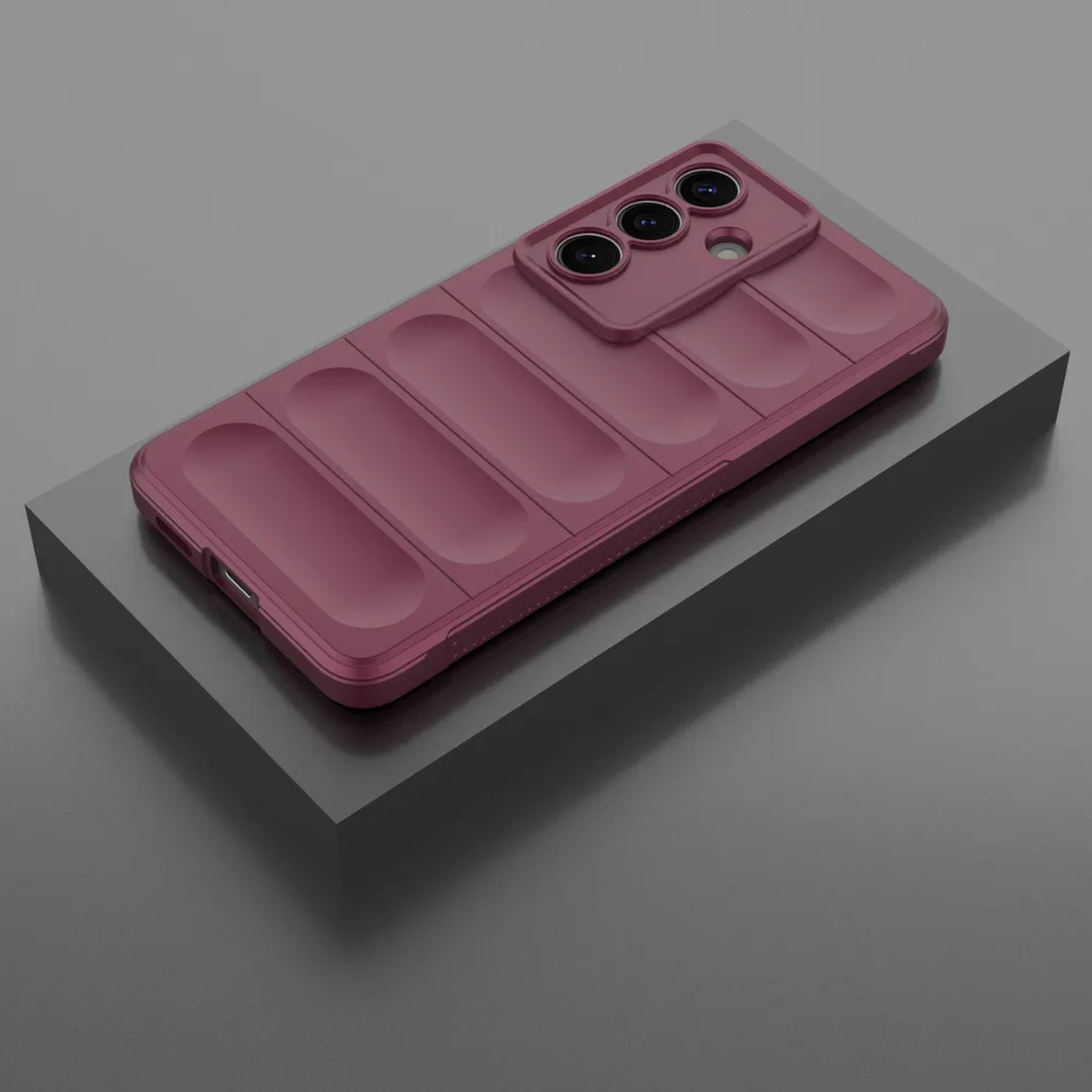 Un téléphone rouge foncé avec système photo repose sur un socle sombre.