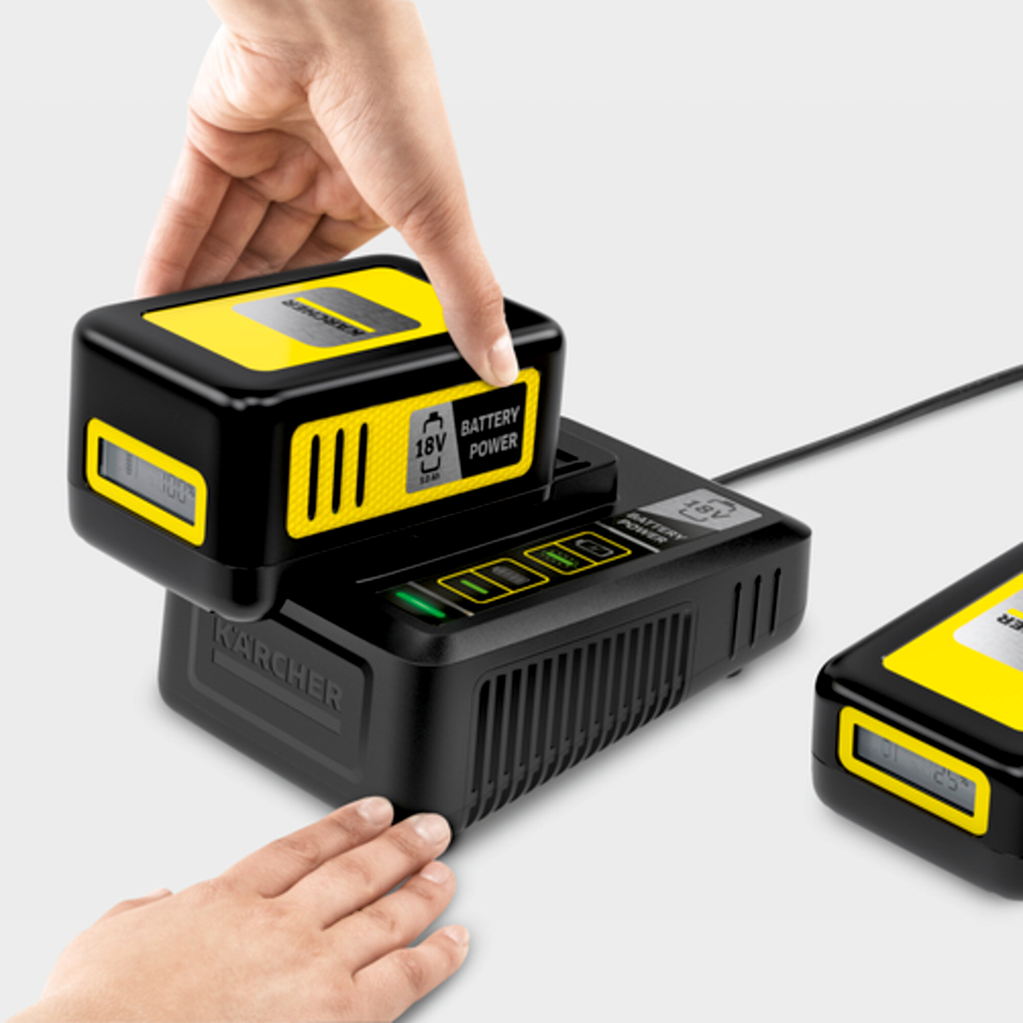 Ręka umieszcza czarny akumulator z żółtym detalem na ładowarce Karcher.