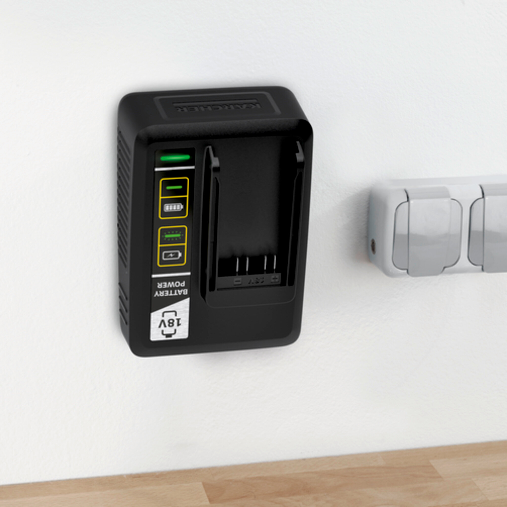 Czarna ładowarka do akumulatorów na białej ścianie, ze wskaźnikami naładowania i symbolem 18V.