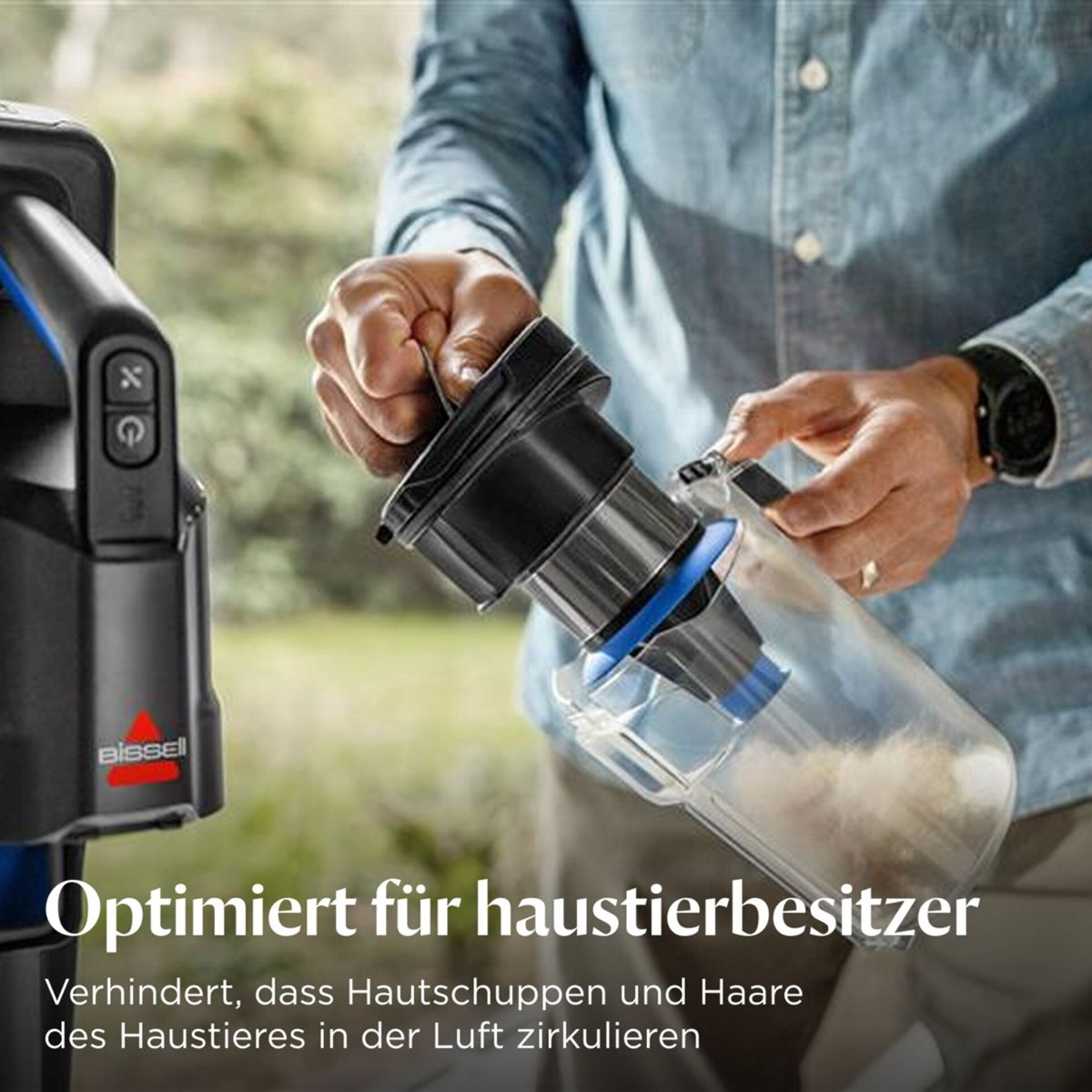Mann hält einen Staubsaugerbehälter mit Staub und Haaren. Bissell-Logo.