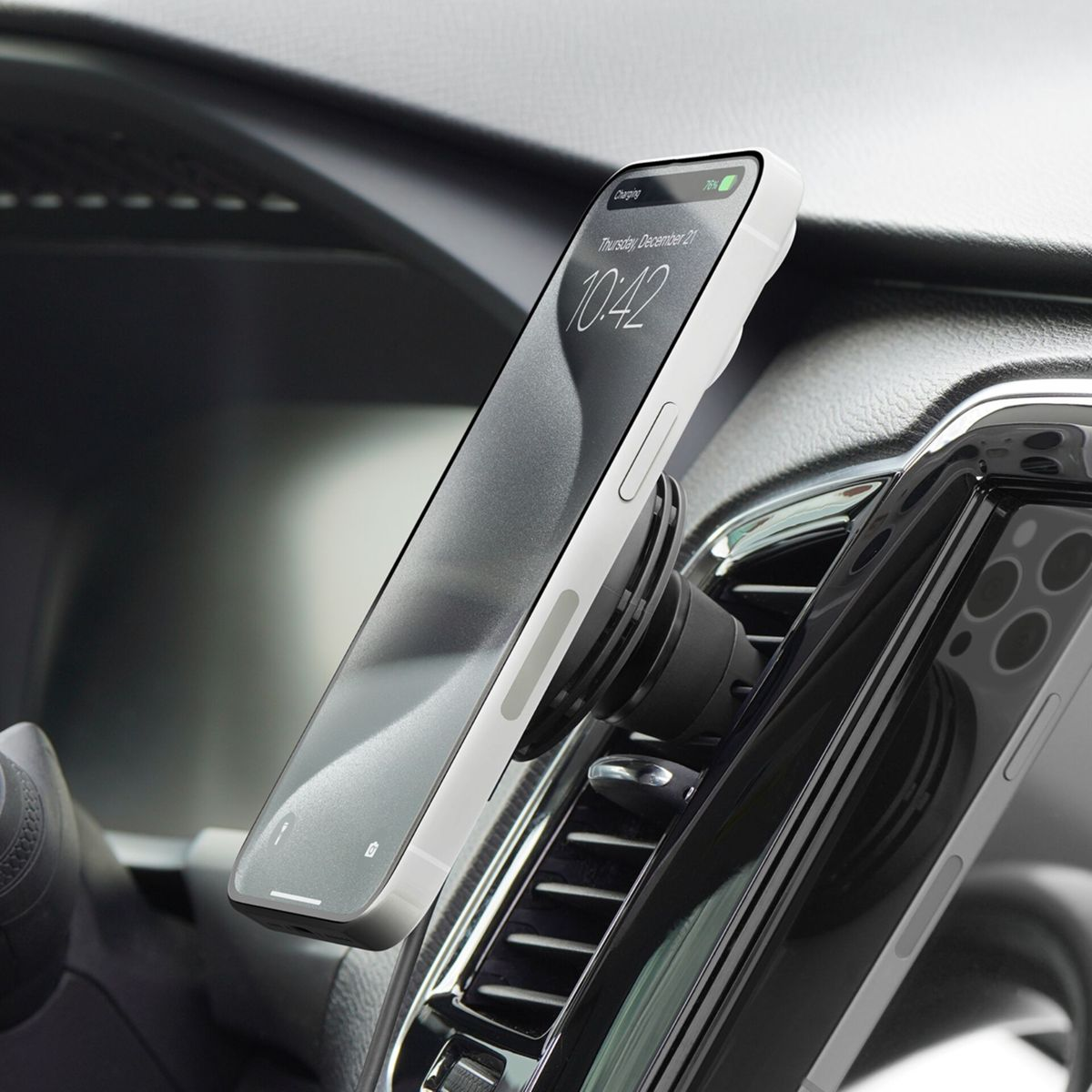 Ein weißes Smartphone ist an einem schwarzen Lüftungshalter in einem Auto befestigt.