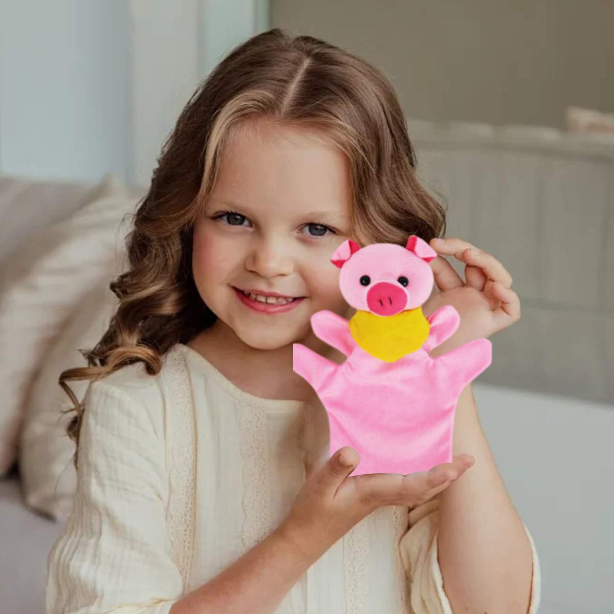 Ein kleines Mädchen hält eine rosa Schweinepuppe mit gelbem Latz.
