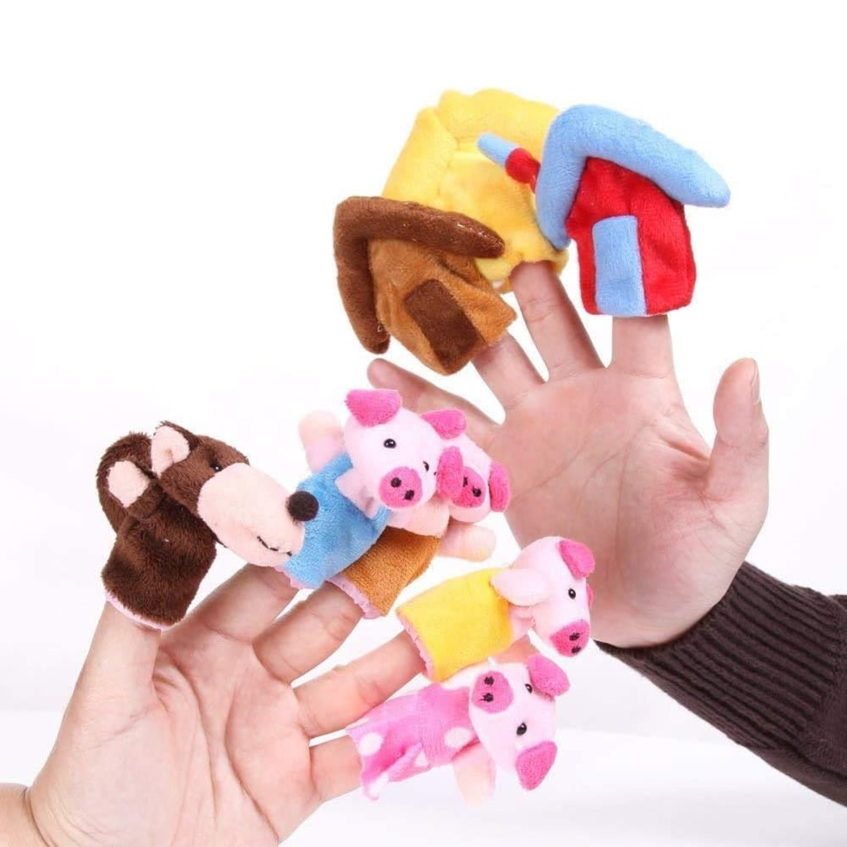 Fingerpuppen von Schweinen und einem Pferd an Fingern mit kleinen Häusern im Hintergrund.