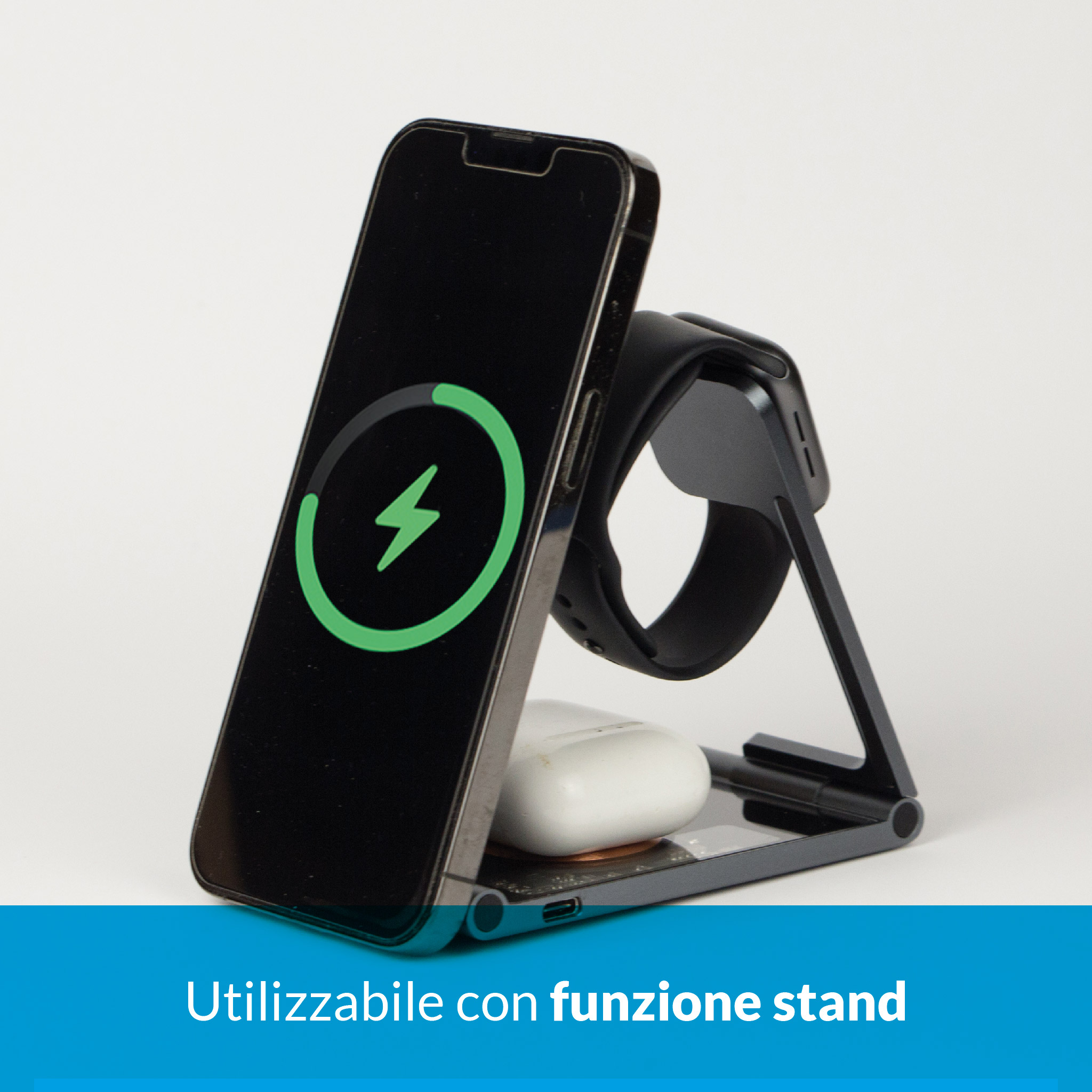 Uno smartphone si carica su un supporto, con un case di ricarica e un orologio nelle vicinanze.