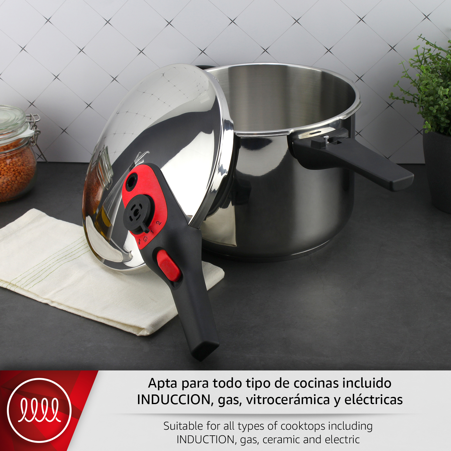 Olla a presión de acero inoxidable con tapa abierta y asa roja. Sobre encimera oscura.