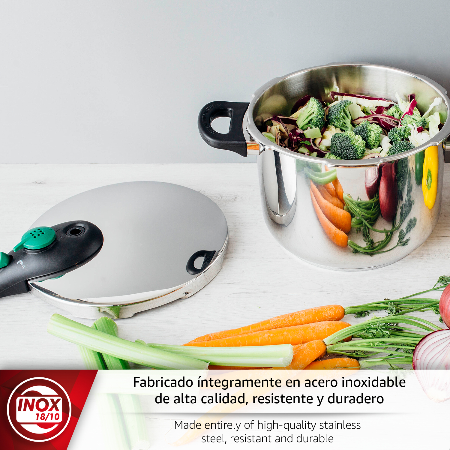 Olla de acero inoxidable con verduras. Tapa al lado. Zanahorias y cebollas delante.